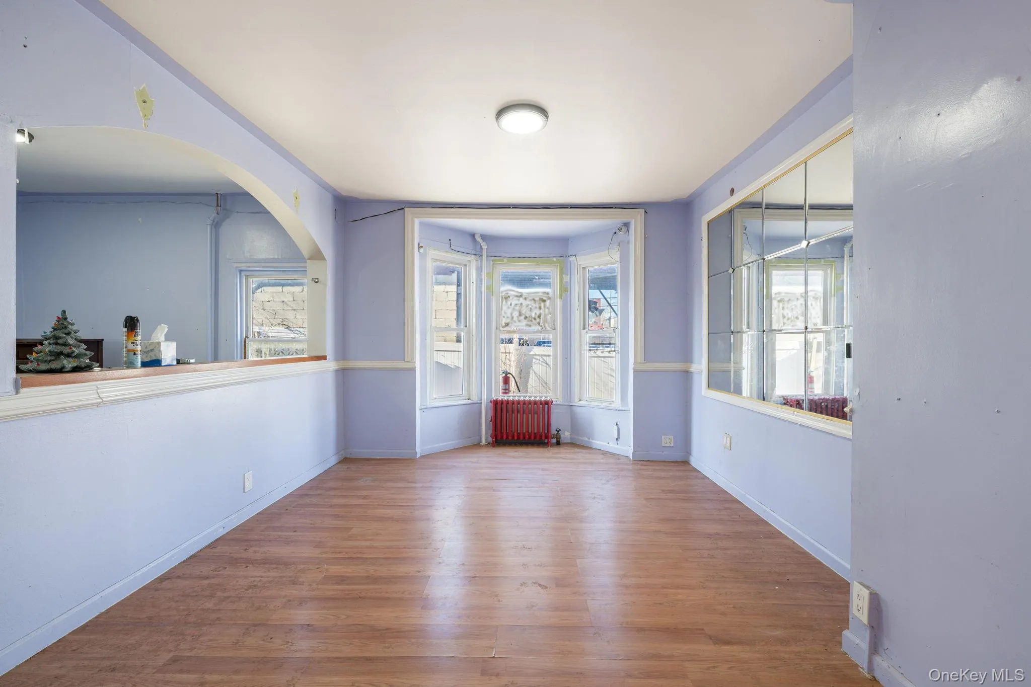 Empty room featuring wood finished floors, radiator heating unit, and healthy amount of natural light Empty room featuring wood finished floors, radiator heating unit, and healthy amount of natural light