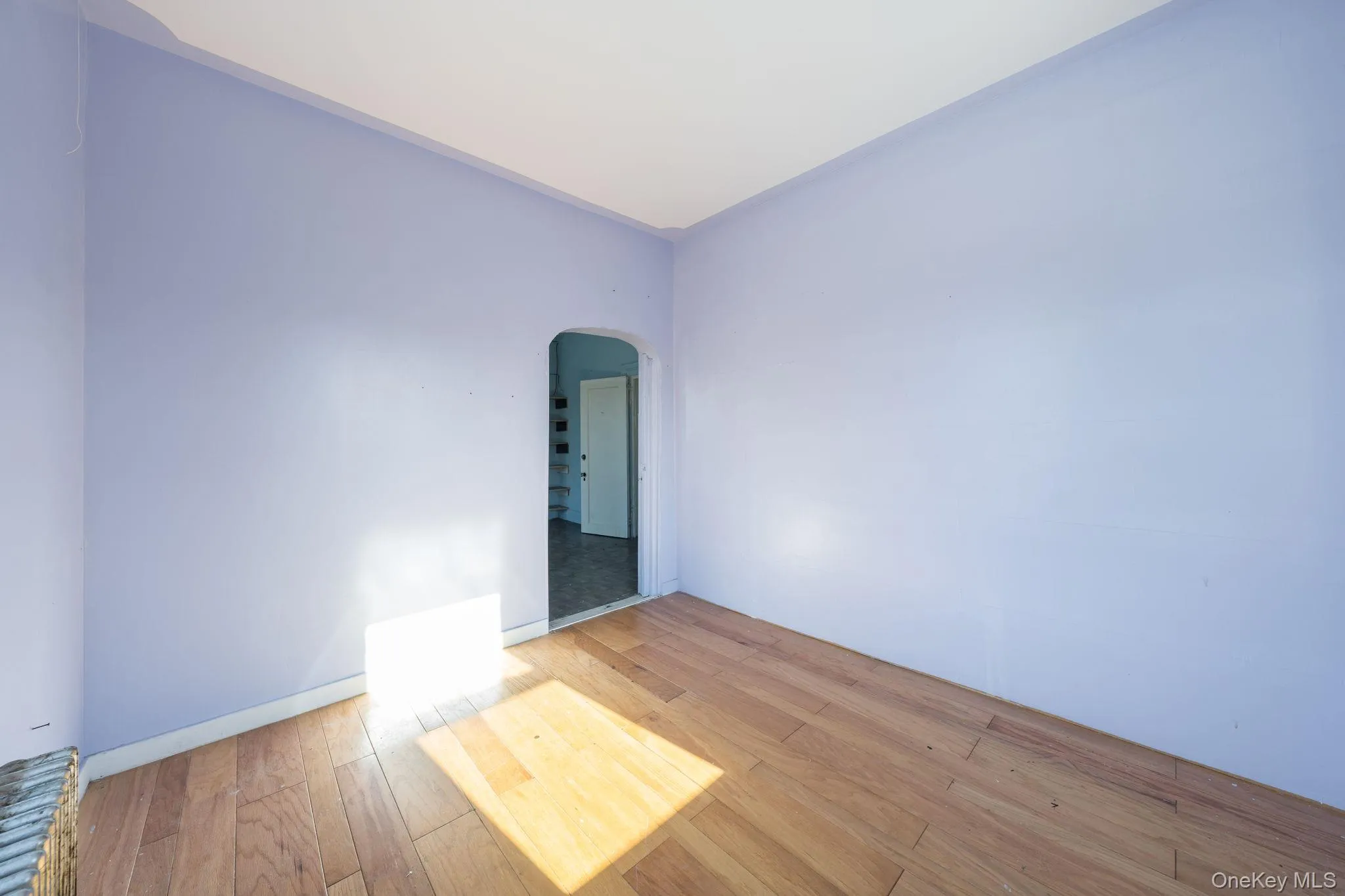 Empty room featuring arched walkways and hardwood / wood-style flooring Empty room featuring arched walkways and hardwood / wood-style flooring