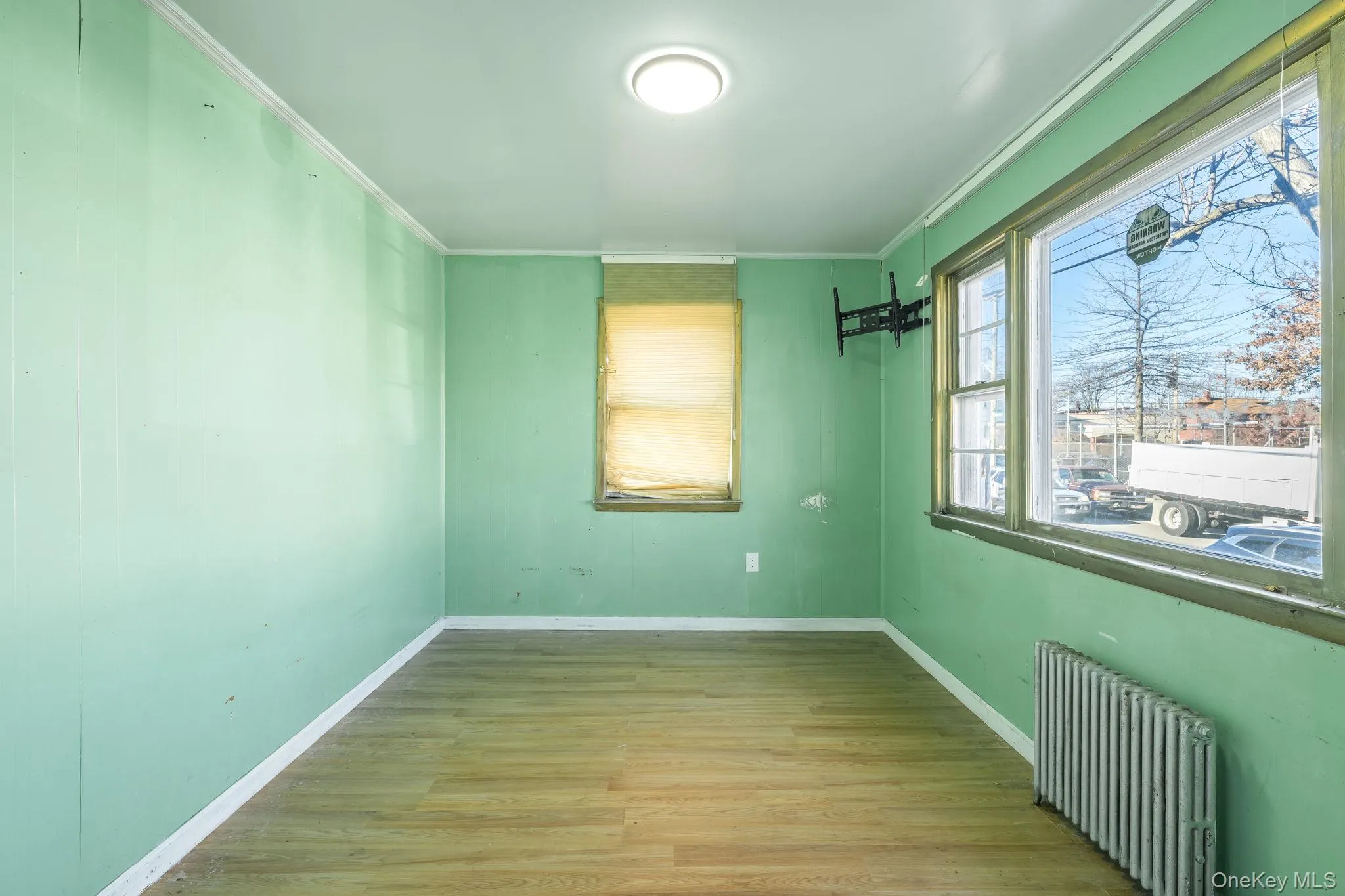 Empty room with radiator, light wood-style flooring, and crown molding Empty room with radiator, light wood-style flooring, and crown molding