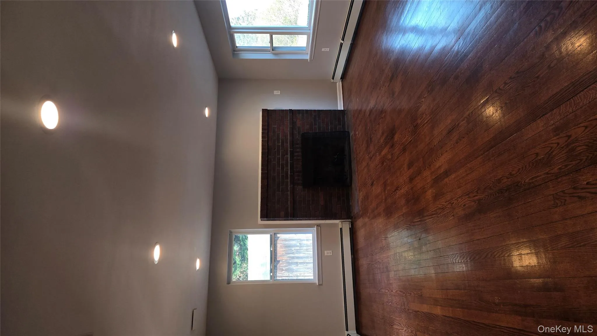 Unfurnished living room with a fireplace, baseboard heating, dark wood finished floors, and recessed lighting Unfurnished living room with a fireplace, baseboard heating, dark wood finished floors, and recessed lighting