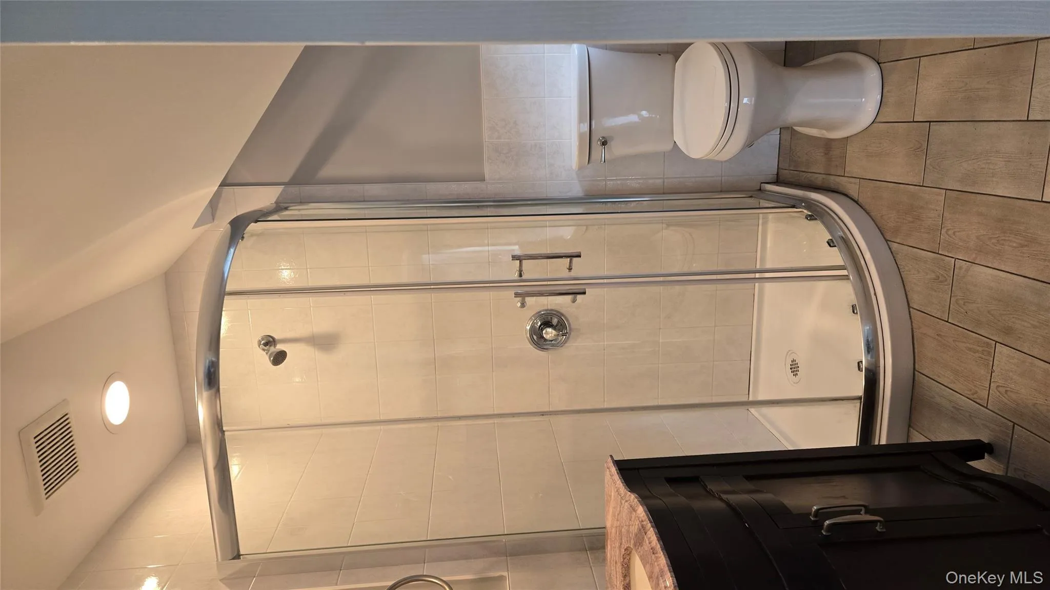 Bathroom with vanity, a shower stall, tile walls, recessed lighting, and a wainscoted wall Bathroom with vanity, a shower stall, tile walls, recessed lighting, and a wainscoted wall