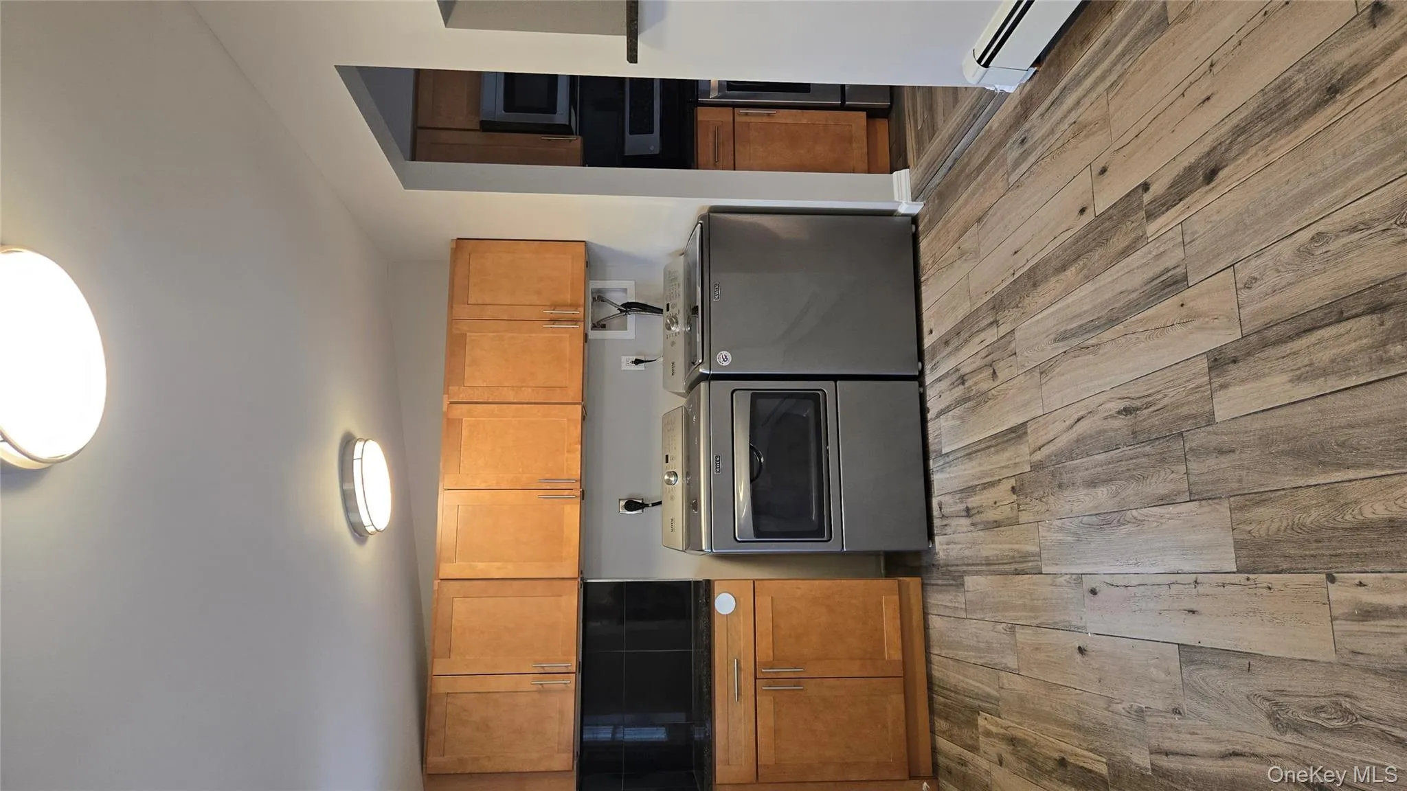 Kitchen with a baseboard heating unit, range, light wood-style floors, brown cabinetry, and washer and dryer Kitchen with a baseboard heating unit, range, light wood-style floors, brown cabinetry, and washer and dryer