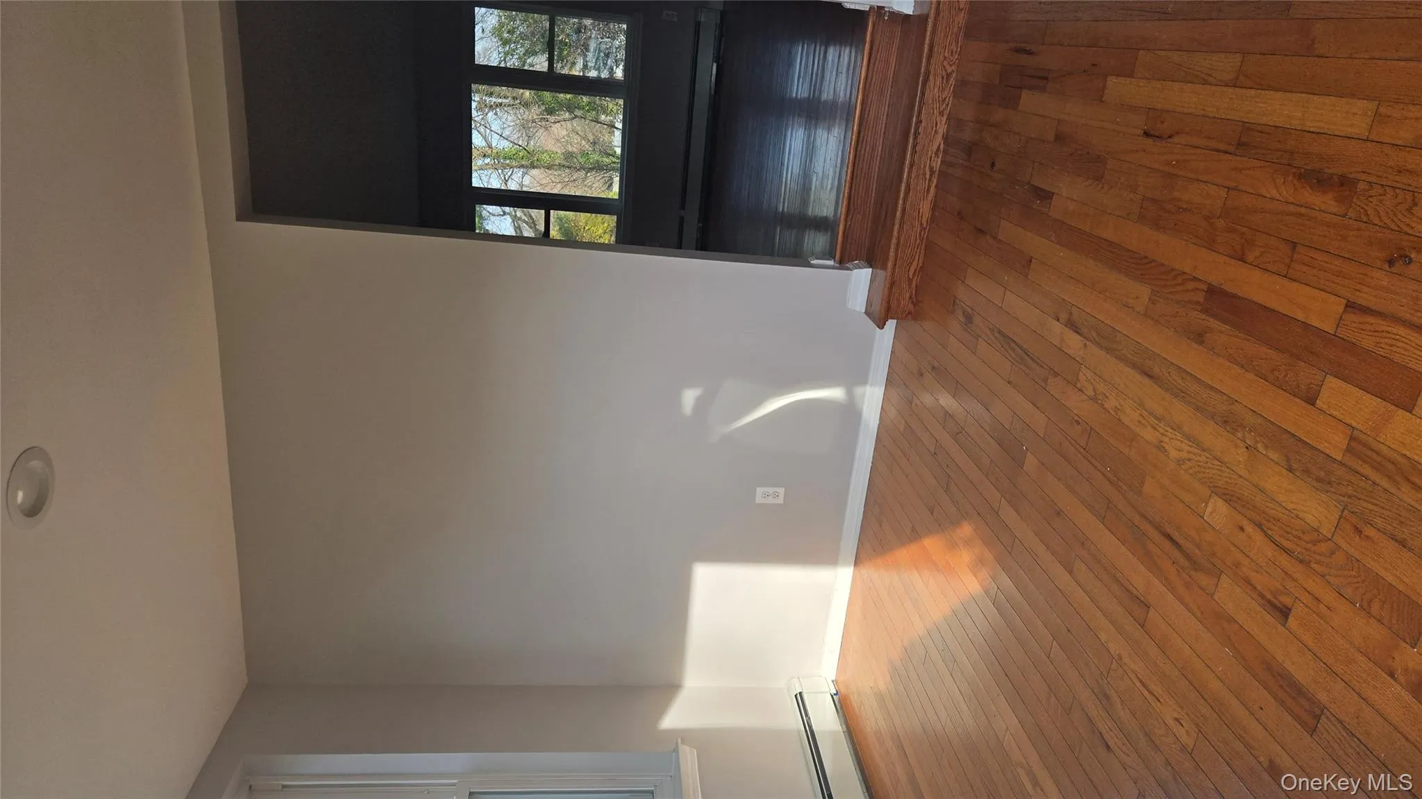 Unfurnished living room featuring a baseboard radiator and hardwood / wood-style floors Unfurnished living room featuring a baseboard radiator and hardwood / wood-style floors