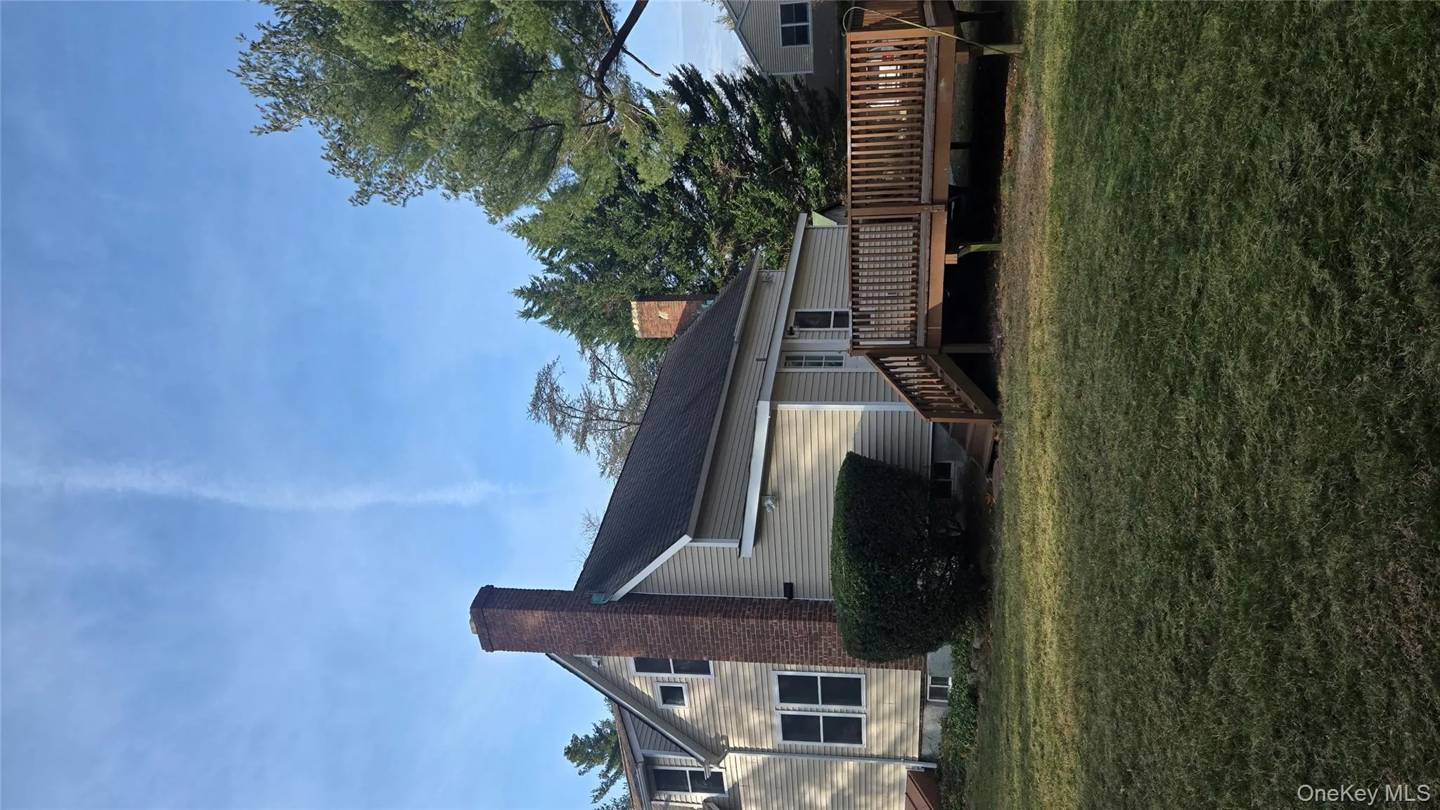 Back of house featuring a chimney, a yard, and a wooden deck Back of house featuring a chimney, a yard, and a wooden deck
