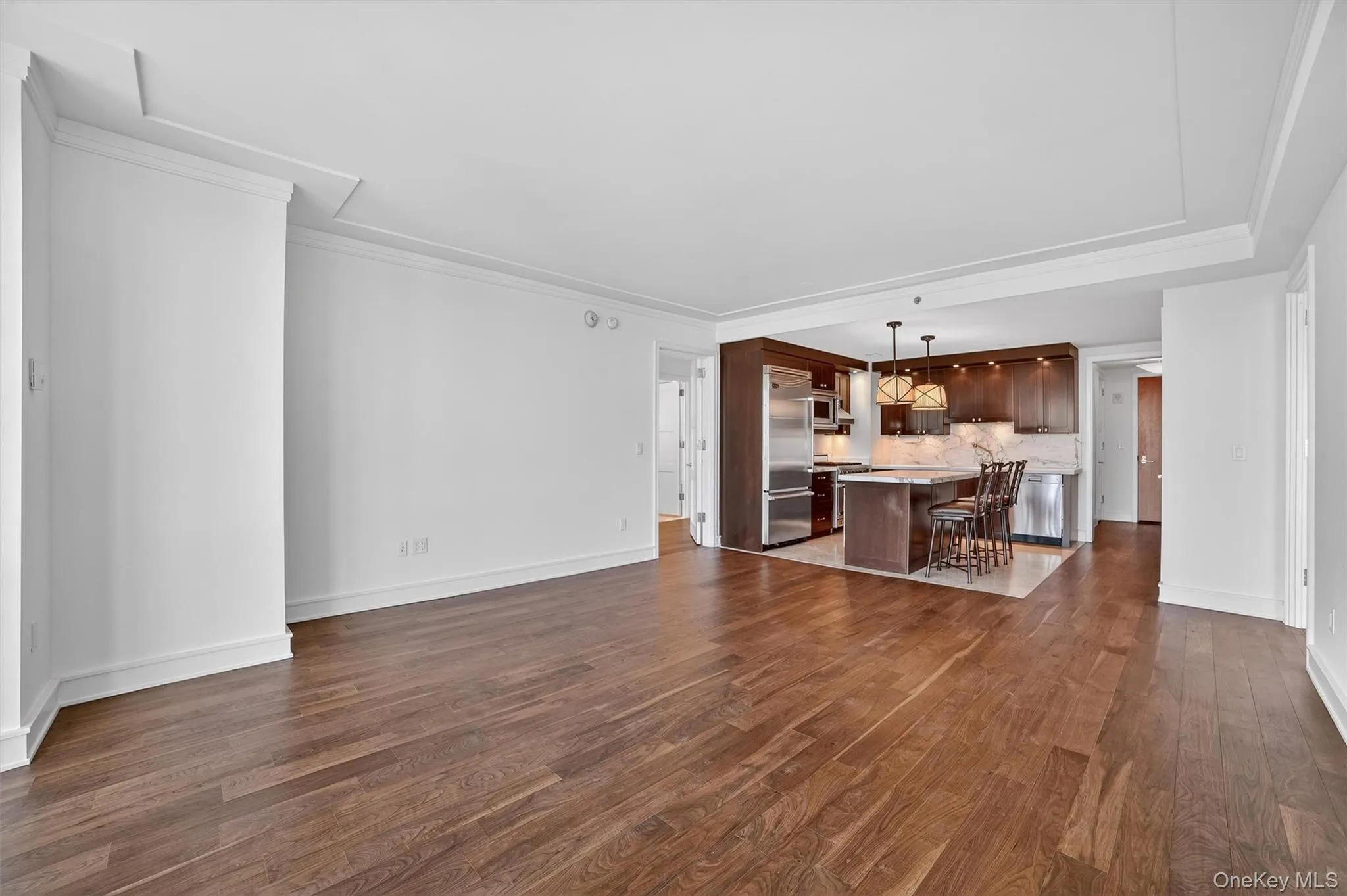 Unfurnished living room with dark wood-style floors and crown molding Unfurnished living room with dark wood-style floors and crown molding