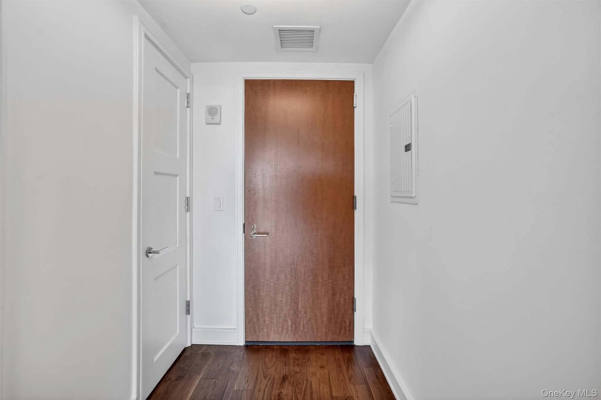 Hallway with electric panel and dark wood finished floors Hallway with electric panel and dark wood finished floors