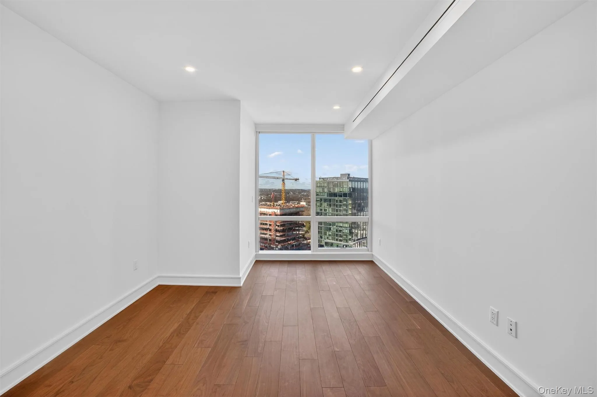 Empty room featuring dark wood-style floors, recessed lighting, and floor to ceiling windows Empty room featuring dark wood-style floors, recessed lighting, and floor to ceiling windows