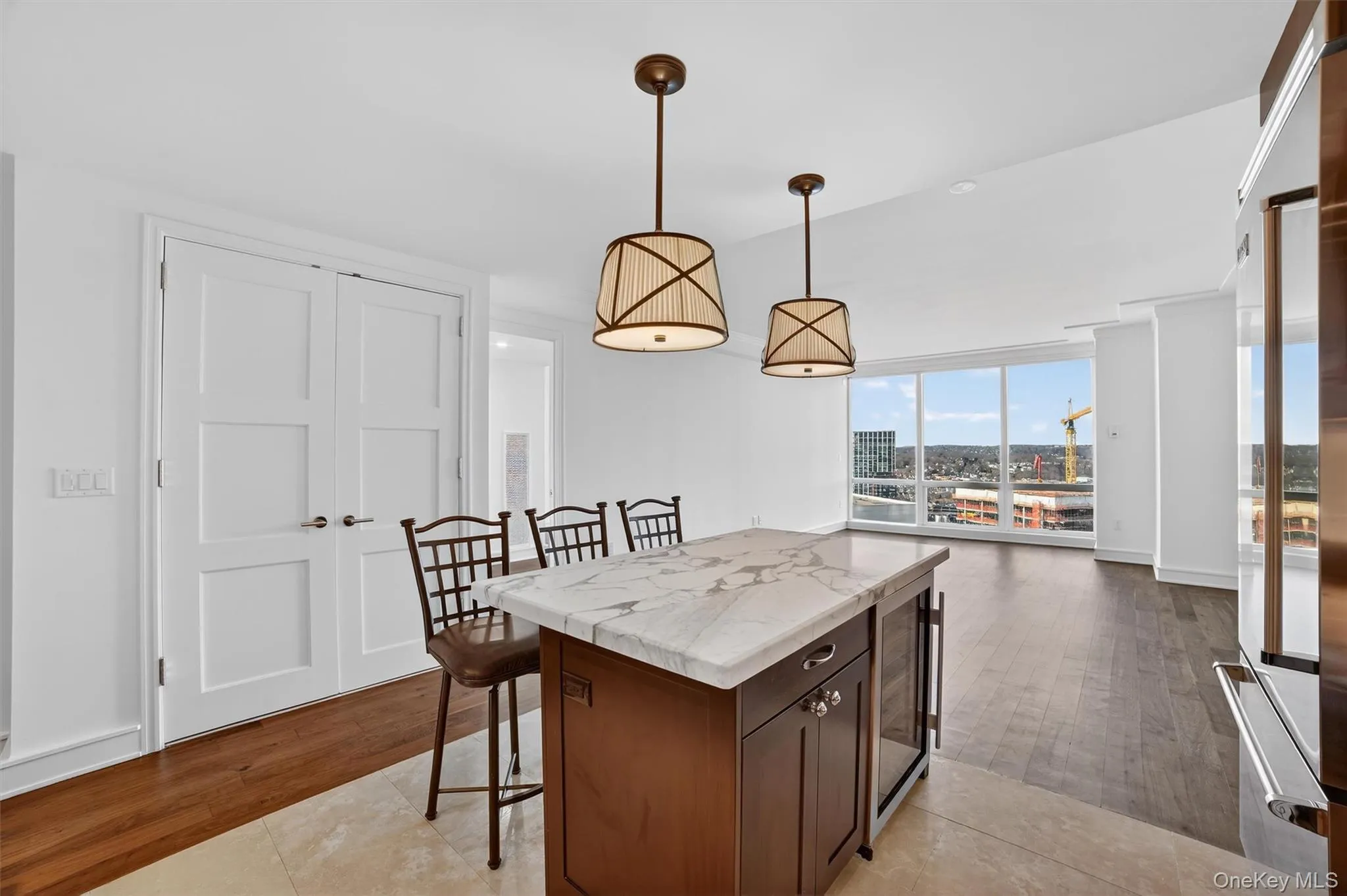 Kitchen featuring a kitchen bar, light wood finished floors, decorative light fixtures, high end refrigerator, and a kitchen island Kitchen featuring a kitchen bar, light wood finished floors, decorative light fixtures, high end refrigerator, and a kitchen island