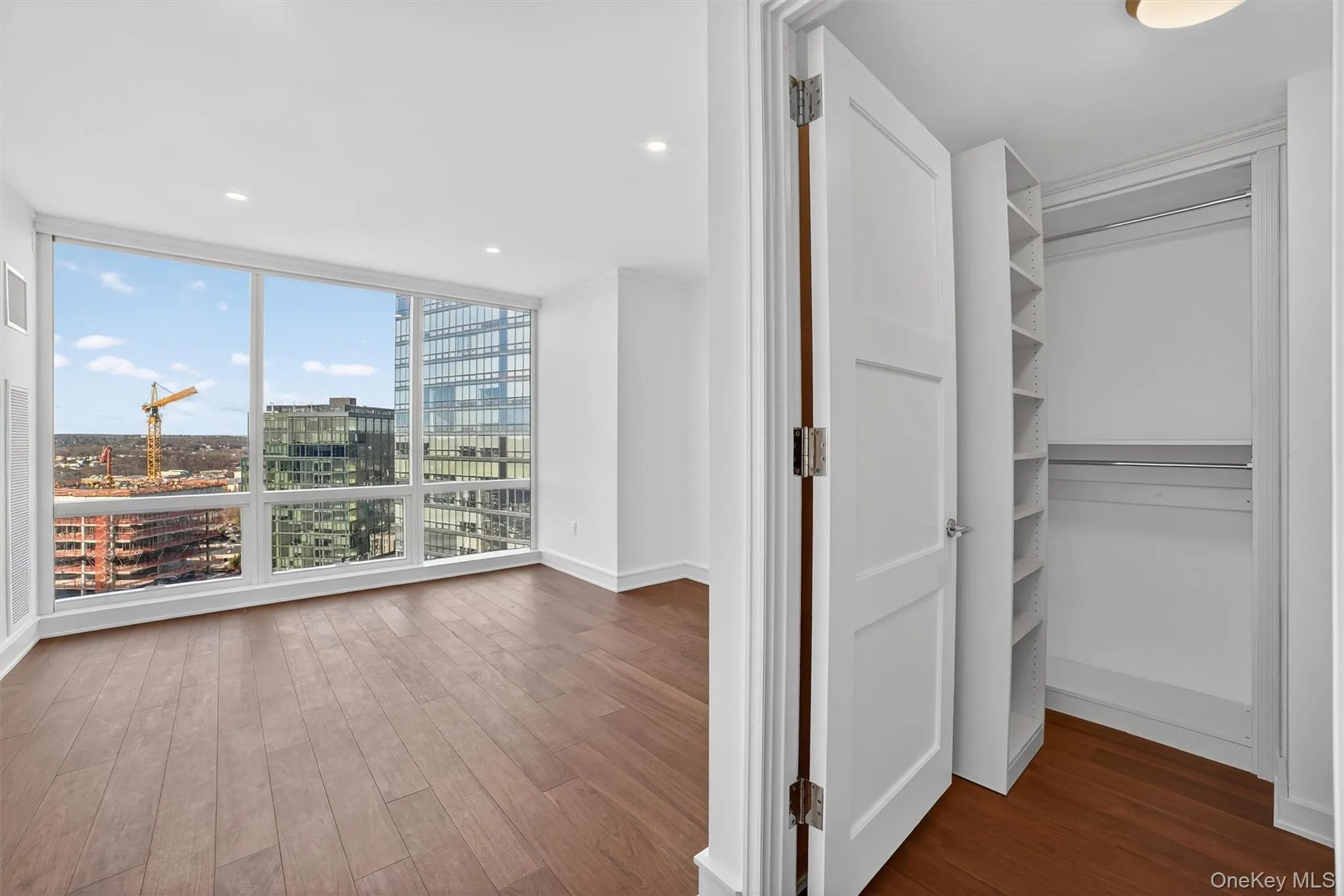 Hall with dark wood finished floors, a city view, floor to ceiling windows, and recessed lighting Hall with dark wood finished floors, a city view, floor to ceiling windows, and recessed lighting