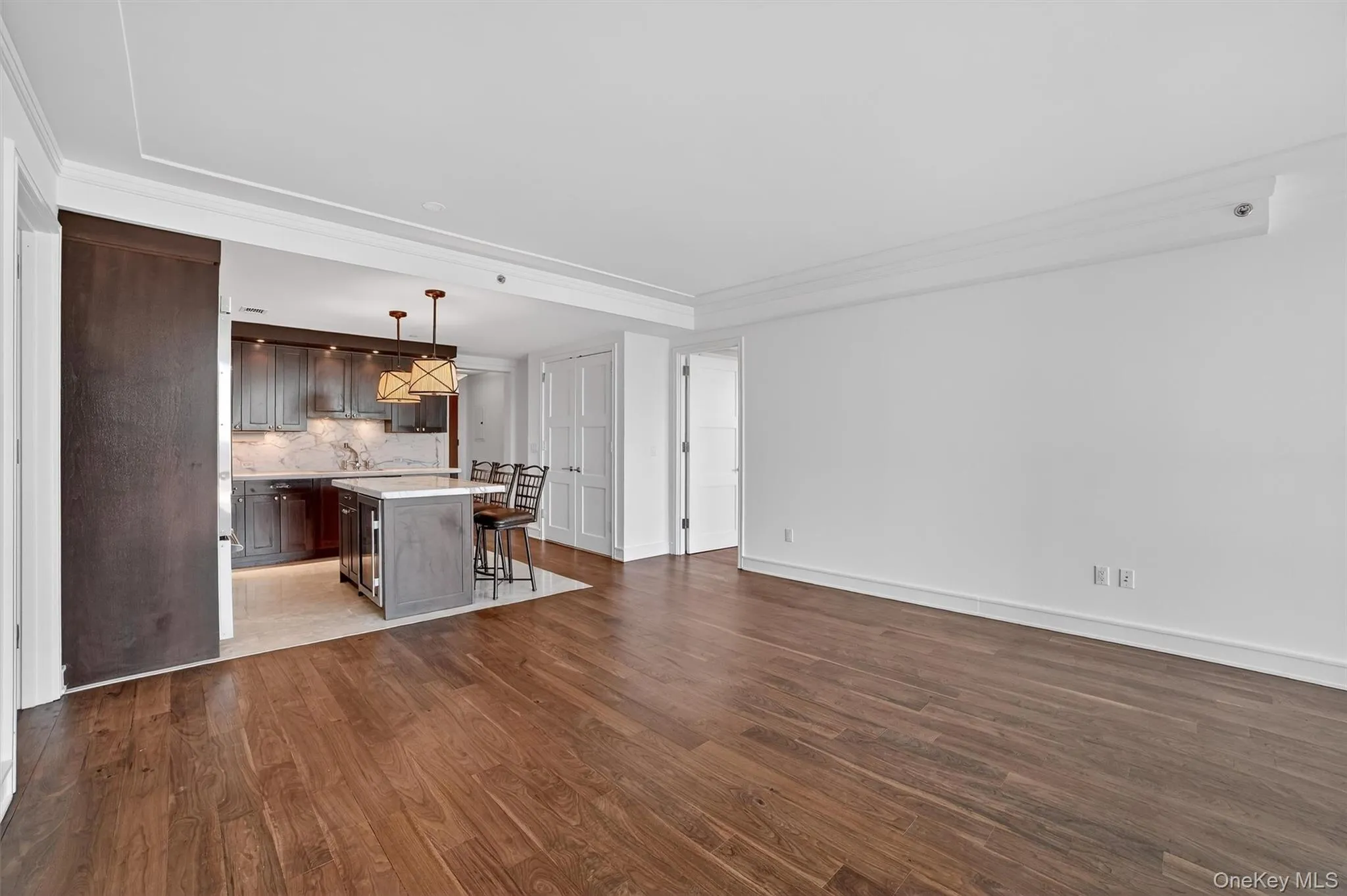 Unfurnished living room featuring dark wood-type flooring and crown molding Unfurnished living room featuring dark wood-type flooring and crown molding