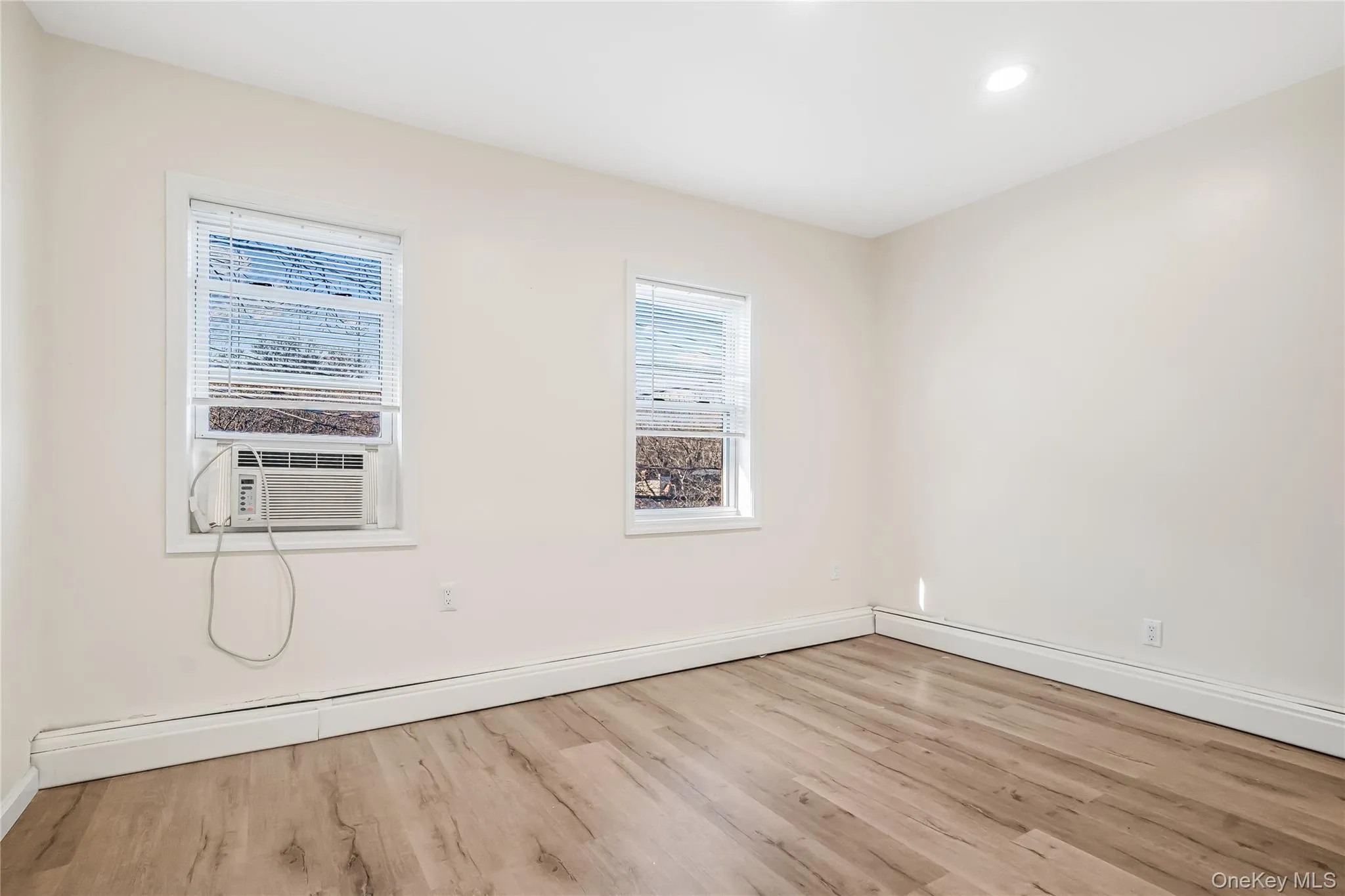 Spare room featuring light wood-style flooring, baseboard heating, recessed lighting, and cooling unit Spare room featuring light wood-style flooring, baseboard heating, recessed lighting, and cooling unit