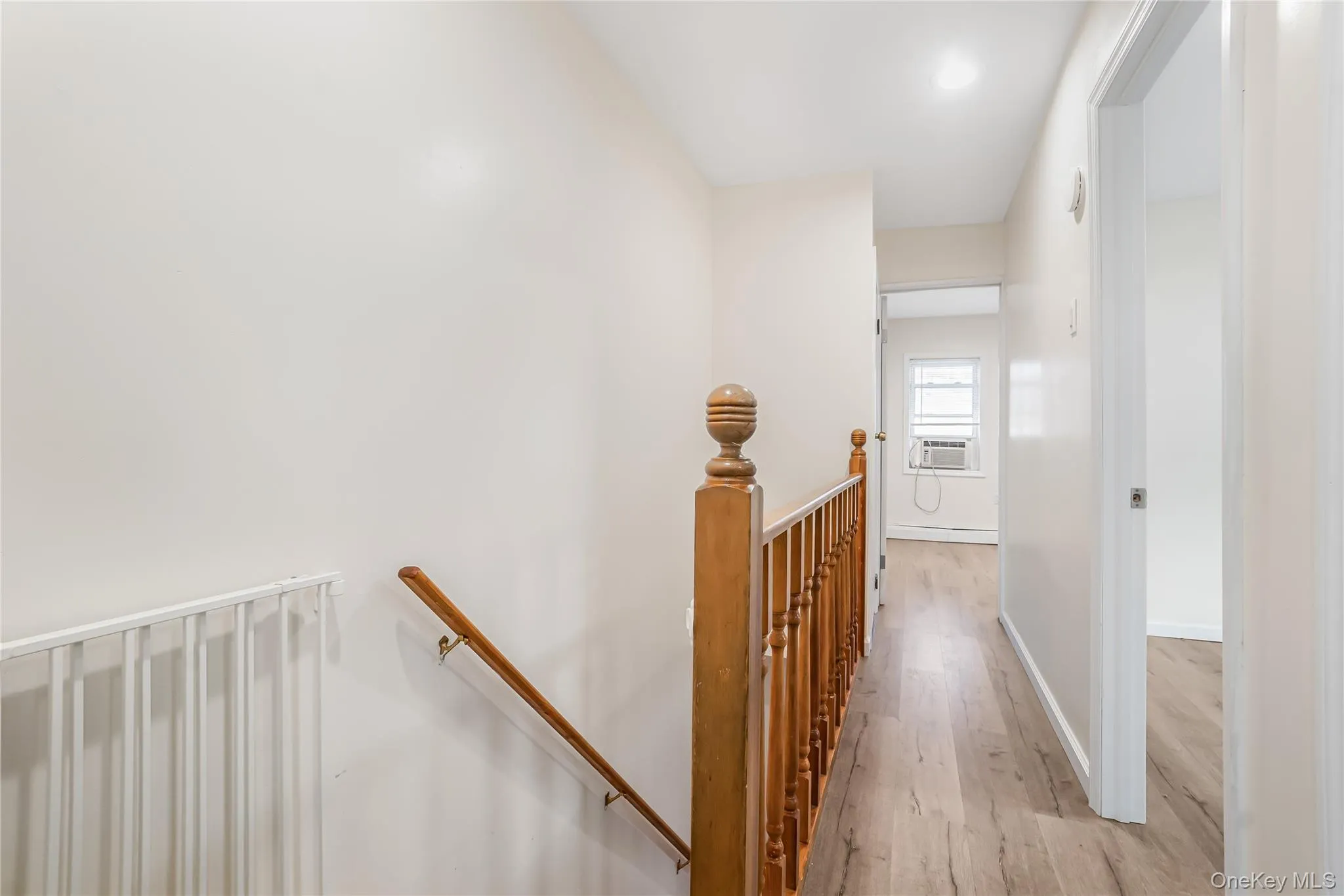 Hall with an upstairs landing and light wood finished floors Hall with an upstairs landing and light wood finished floors