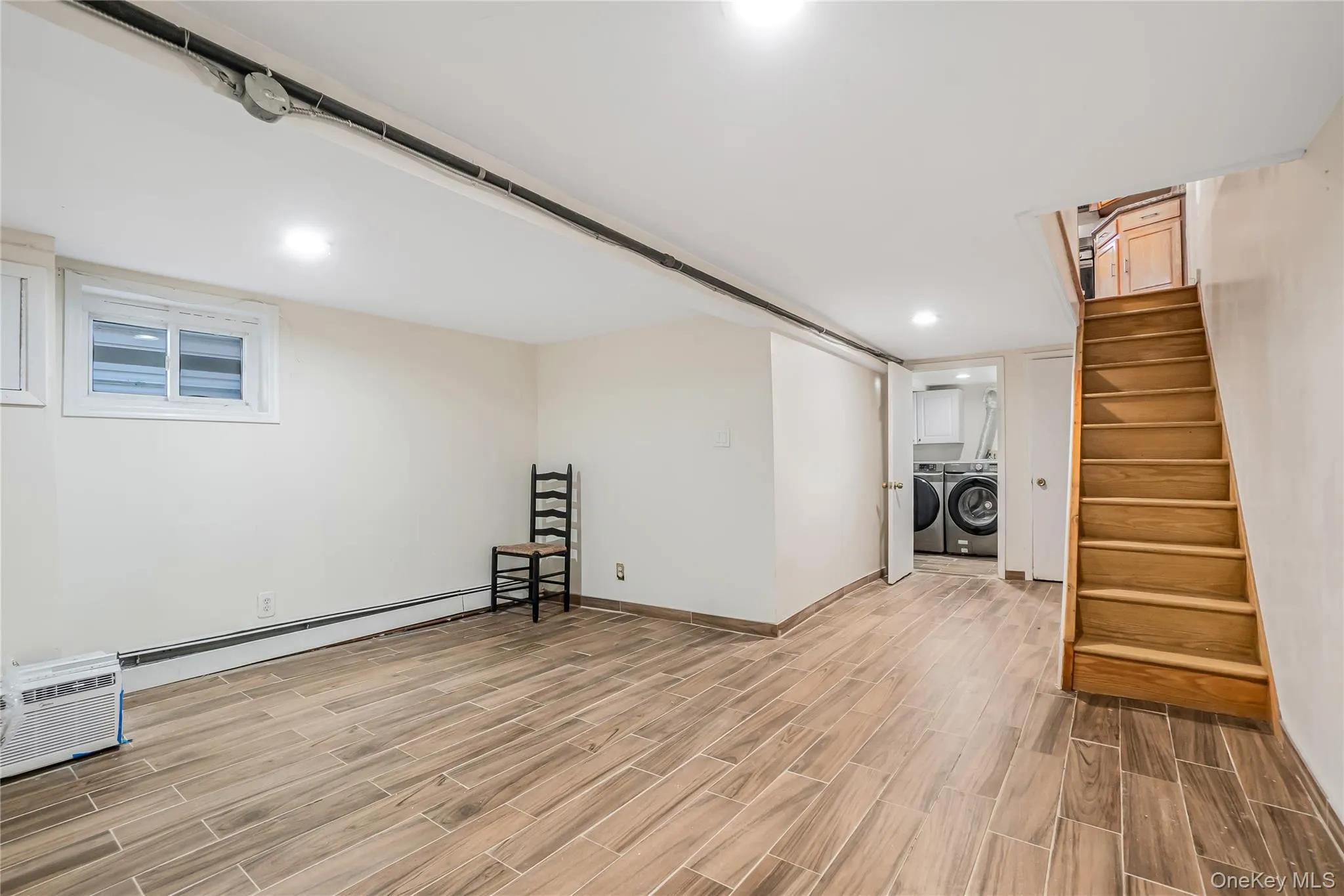 Finished basement with wood tiled floors, stairs, washing machine and clothes dryer, a baseboard radiator, and recessed lighting Finished basement with wood tiled floors, stairs, washing machine and clothes dryer, a baseboard radiator, and recessed lighting