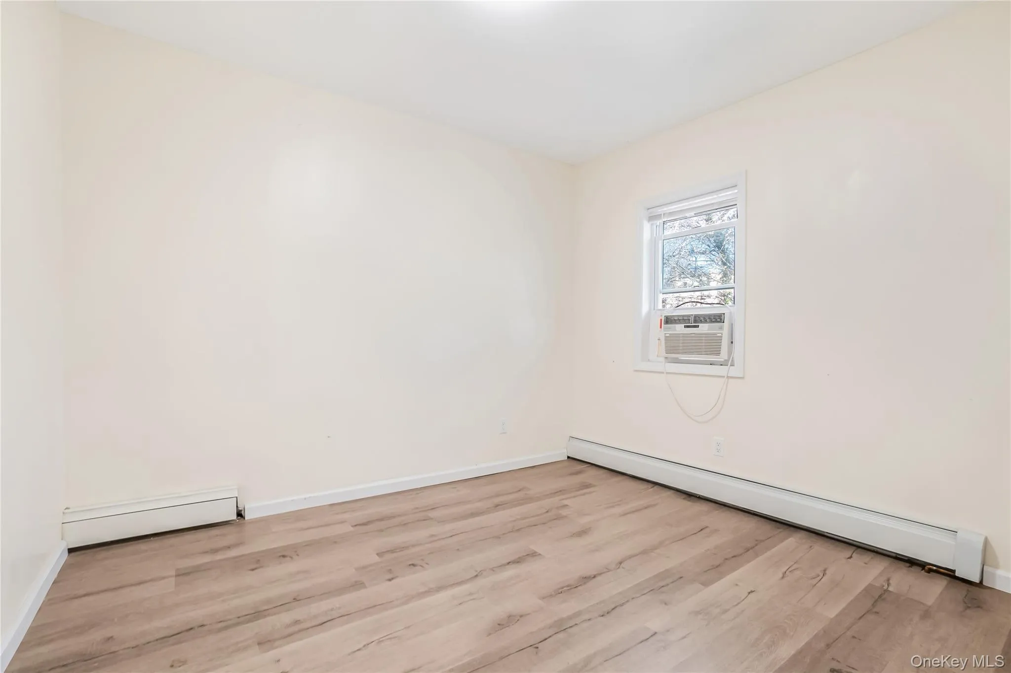 Spare room featuring a baseboard radiator, wood finished floors, and cooling unit Spare room featuring a baseboard radiator, wood finished floors, and cooling unit