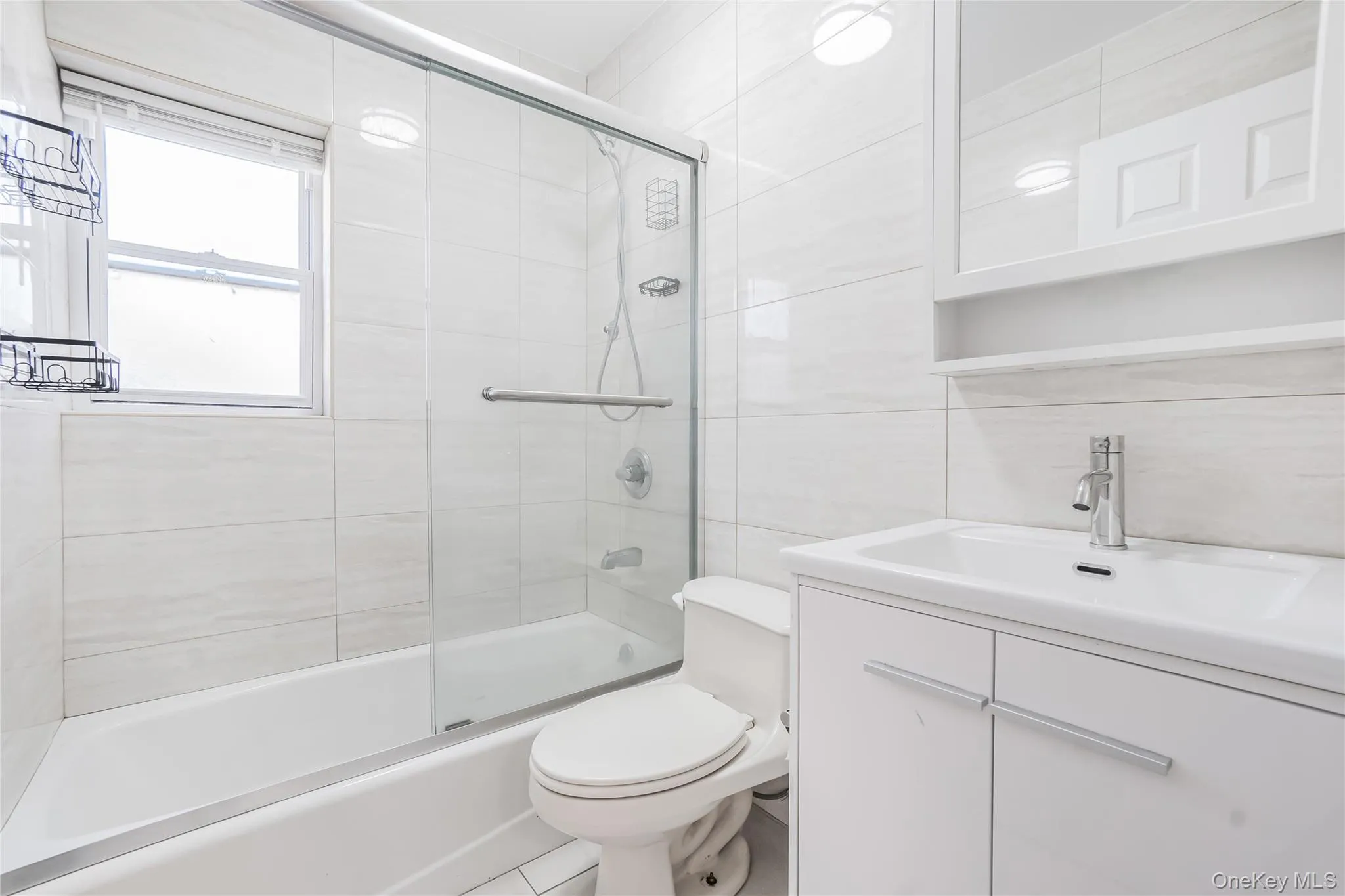 Full bath featuring tile walls, vanity, tasteful backsplash, and enclosed tub / shower combo Full bath featuring tile walls, vanity, tasteful backsplash, and enclosed tub / shower combo