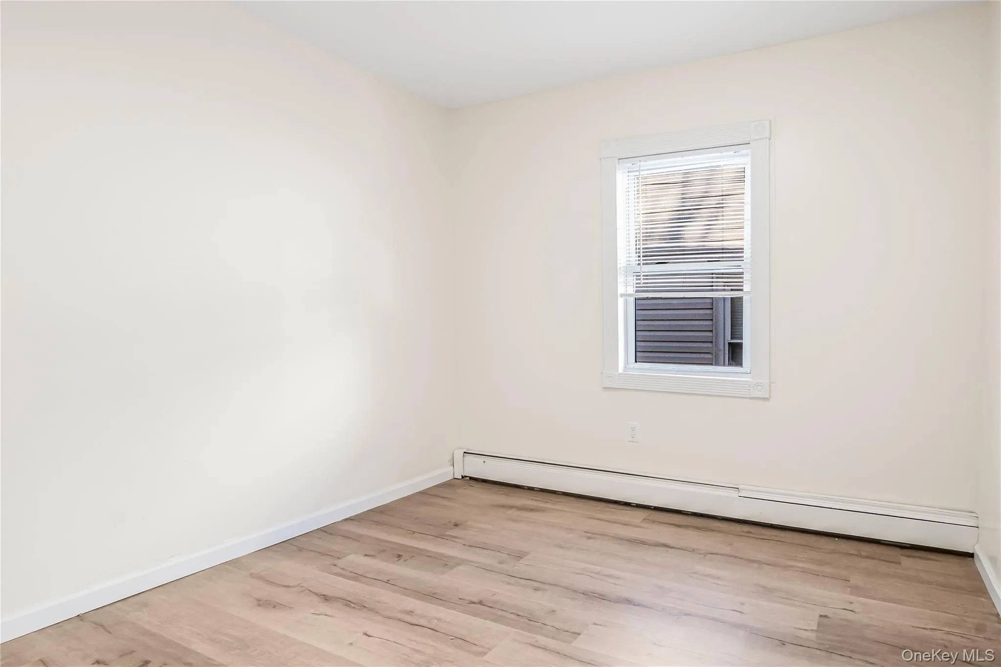 Empty room with baseboard heating and light wood-style floors Empty room with baseboard heating and light wood-style floors