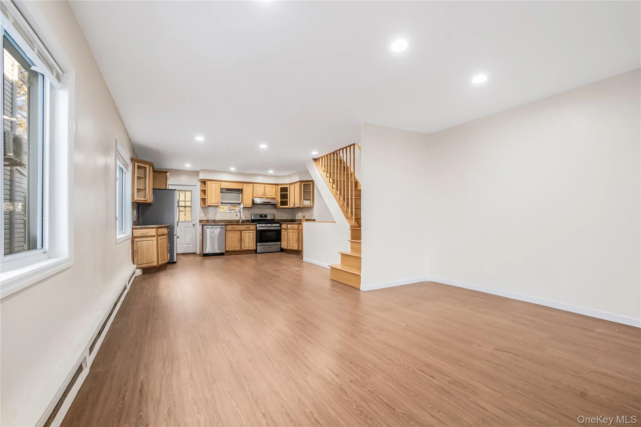 Unfurnished living room featuring stairway, baseboard heating, recessed lighting, and light wood-style flooring Unfurnished living room featuring stairway, baseboard heating, recessed lighting, and light wood-style flooring
