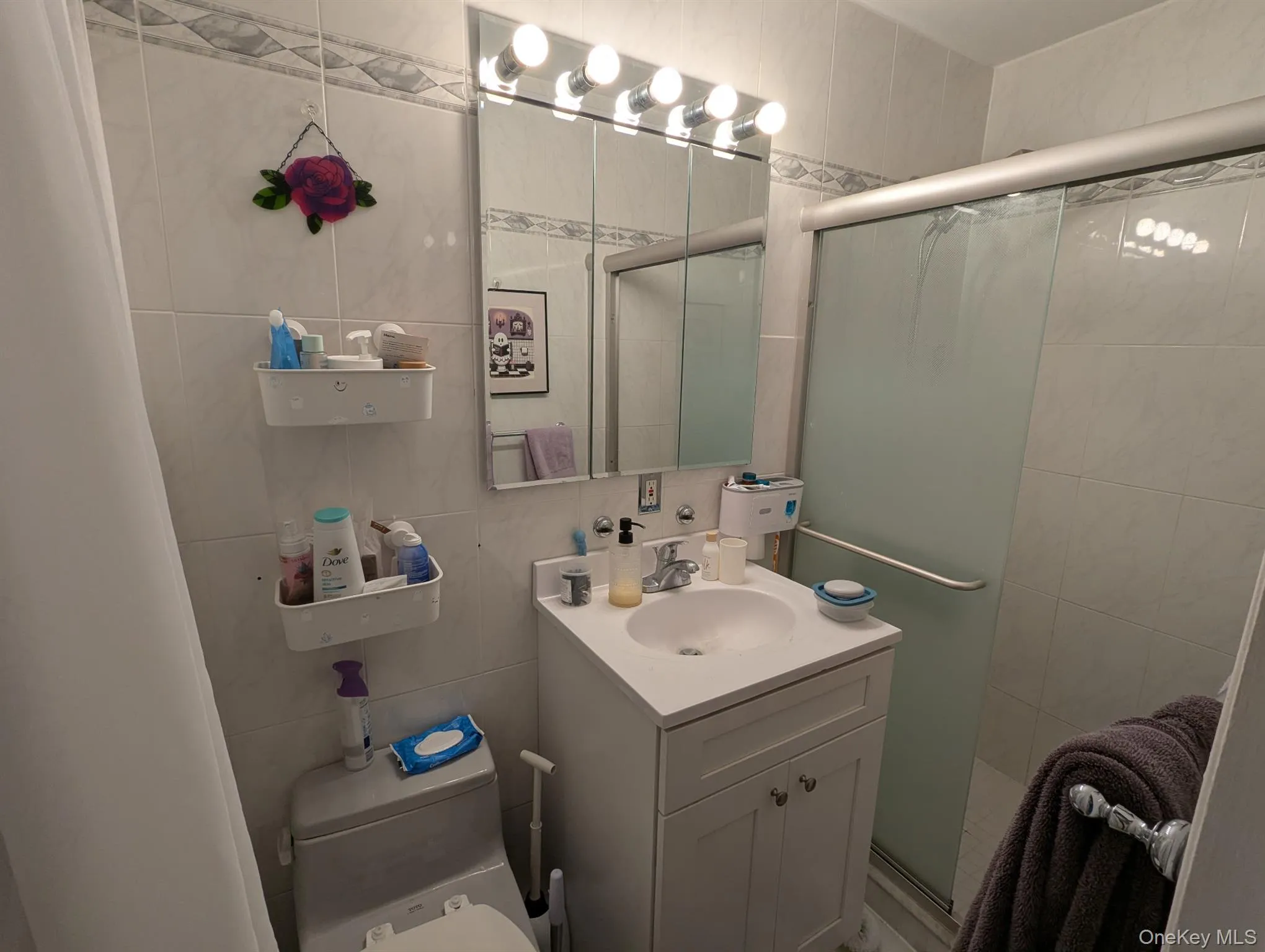 Bathroom featuring vanity, tile walls, and a shower stall Bathroom featuring vanity, tile walls, and a shower stall