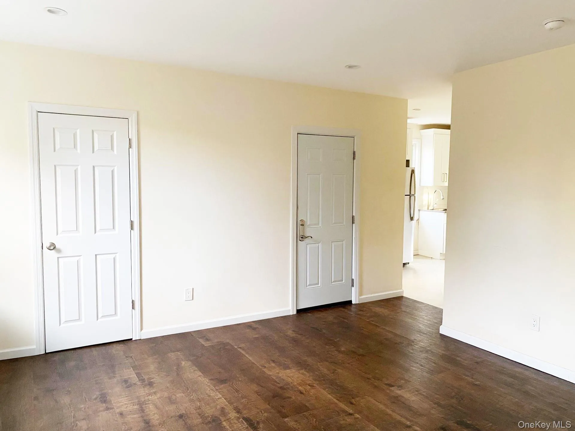 Unfurnished bedroom with dark wood-style flooring and freestanding refrigerator Unfurnished bedroom with dark wood-style flooring and freestanding refrigerator