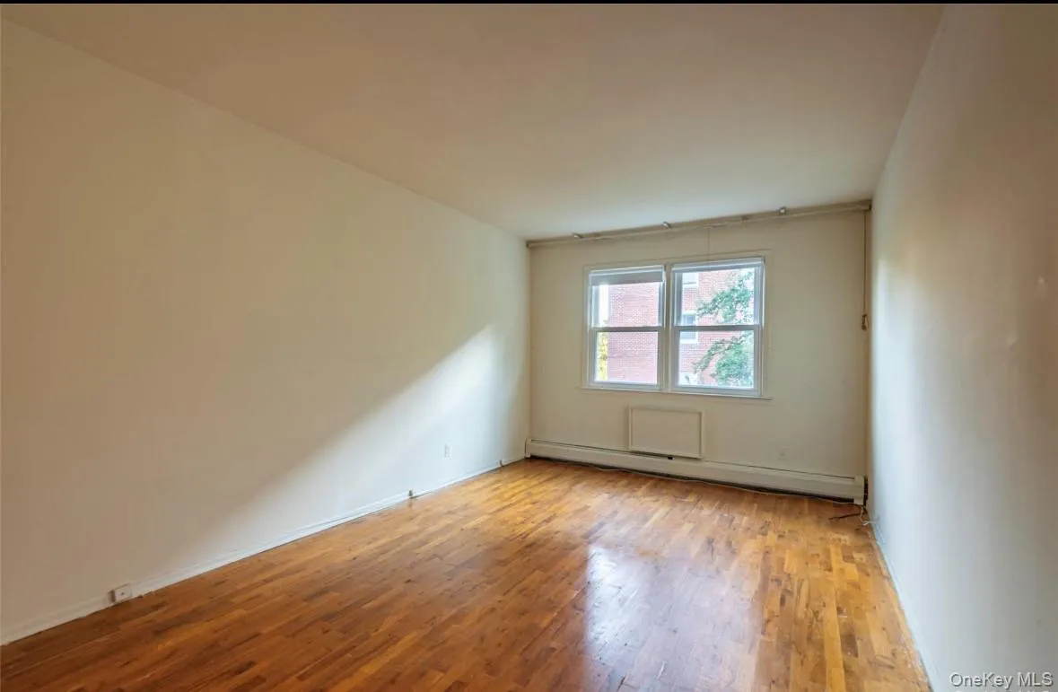 Spare room featuring light wood-style floors and a baseboard radiator Spare room featuring light wood-style floors and a baseboard radiator