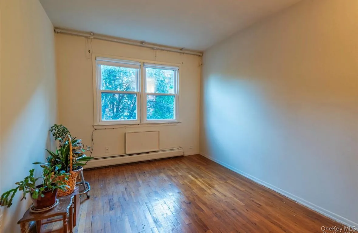 Empty room with a baseboard heating unit and wood-type flooring Empty room with a baseboard heating unit and wood-type flooring