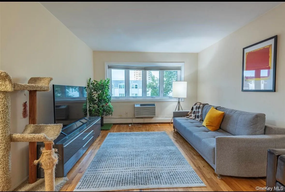 Living room featuring hardwood / wood-style flooring, a baseboard heating unit, and a wall mounted AC Living room featuring hardwood / wood-style flooring, a baseboard heating unit, and a wall mounted AC