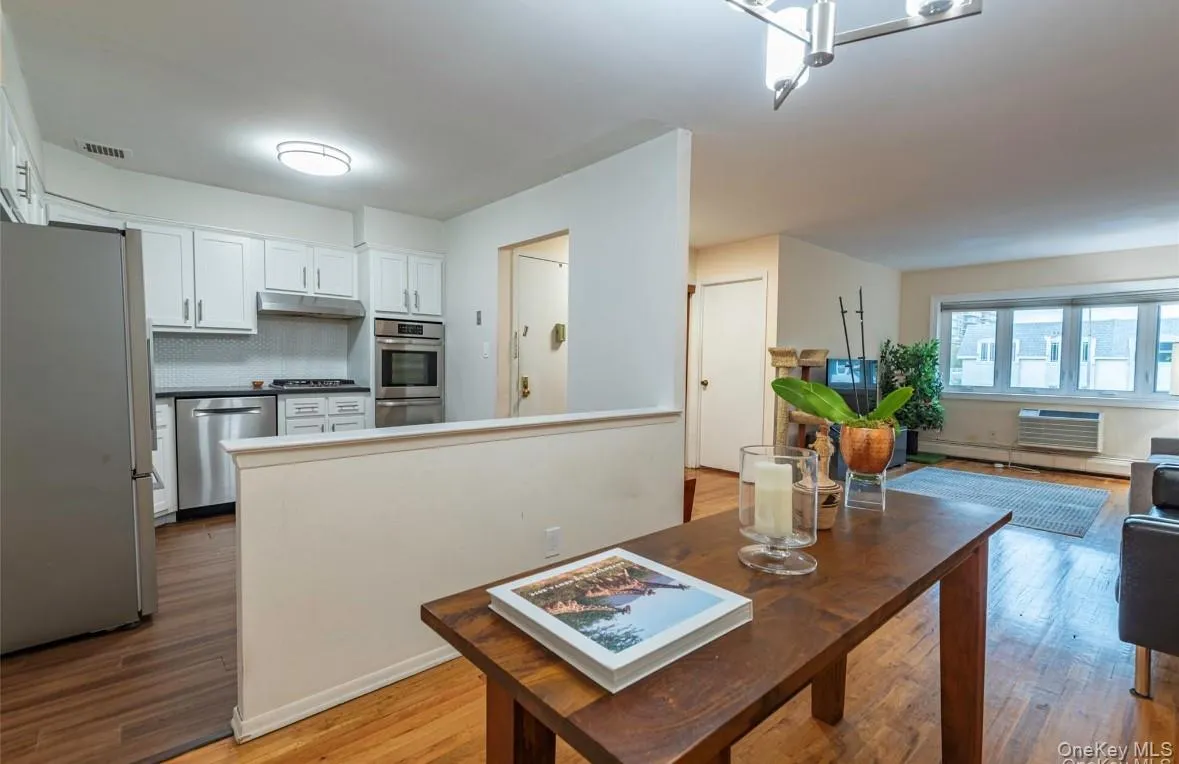 Dining space with light wood-style flooring, a wall mounted AC, and baseboard heating Dining space with light wood-style flooring, a wall mounted AC, and baseboard heating