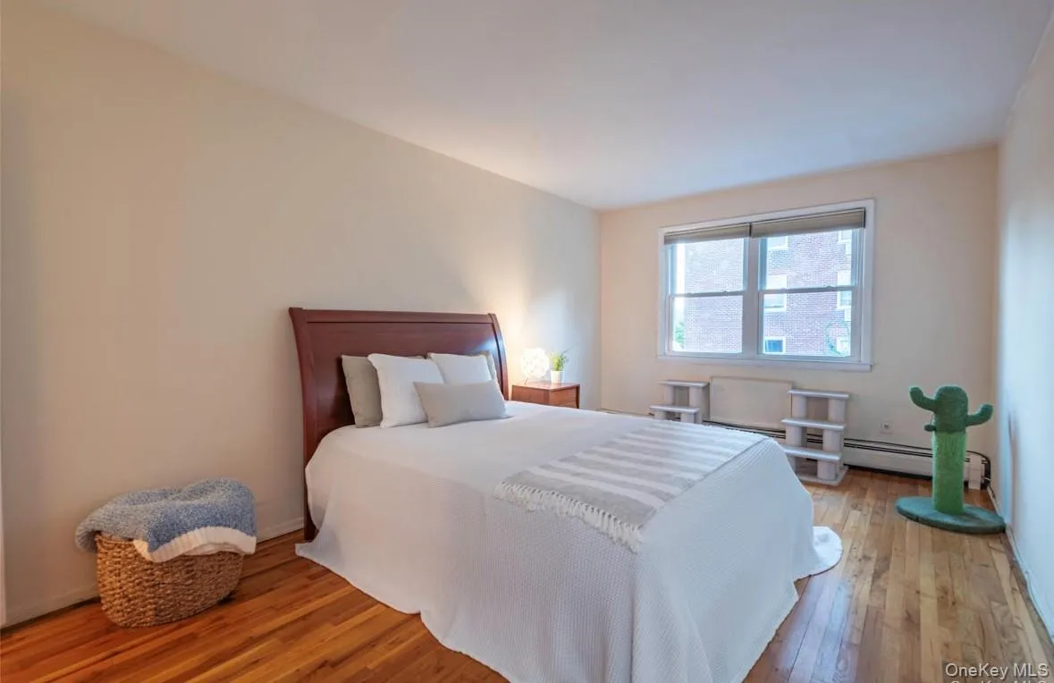 Bedroom with wood-type flooring, a baseboard radiator, and a baseboard heating unit Bedroom with wood-type flooring, a baseboard radiator, and a baseboard heating unit