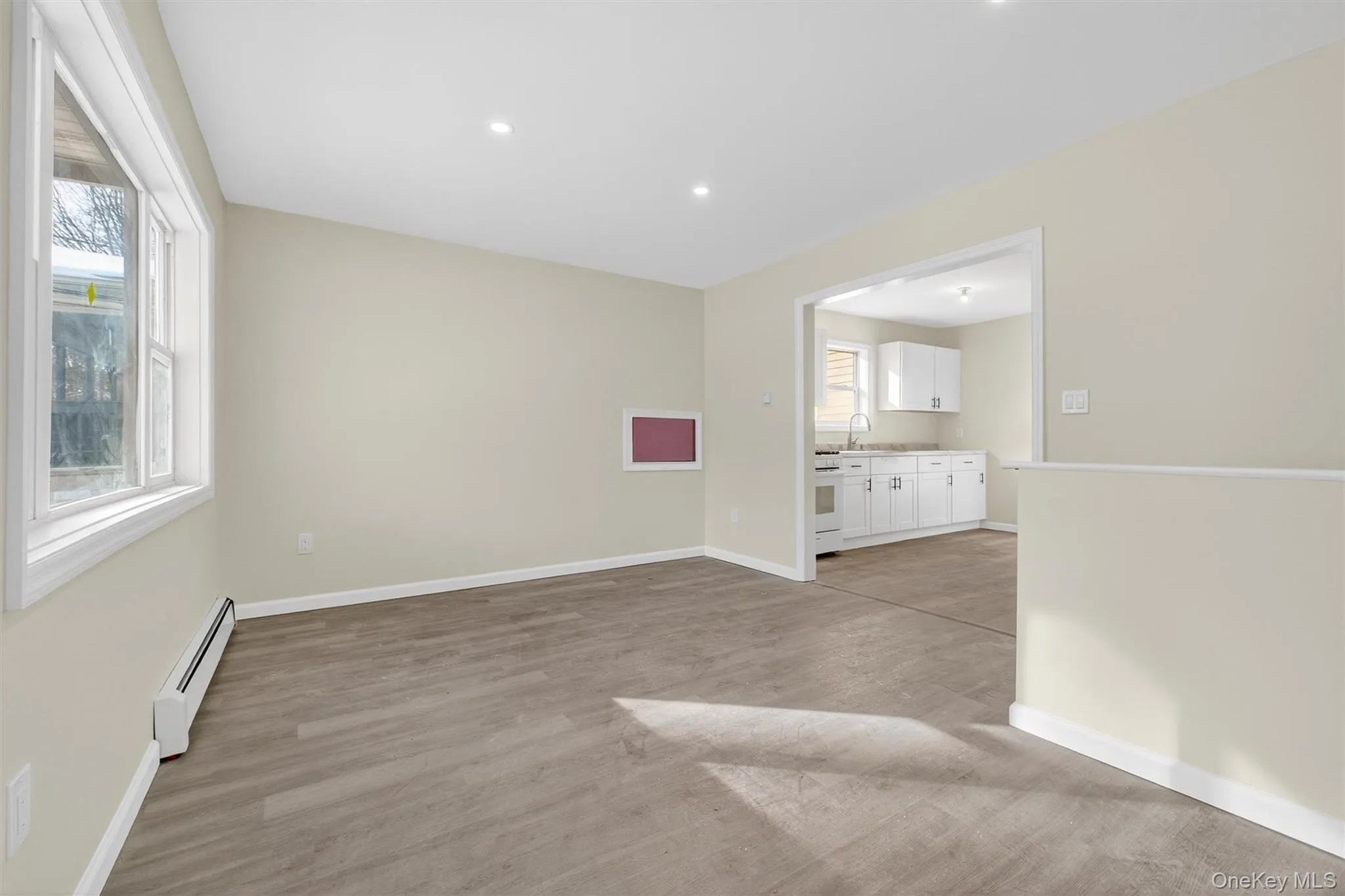 Empty room with baseboard heating, light wood-style flooring, and recessed lighting Empty room with baseboard heating, light wood-style flooring, and recessed lighting