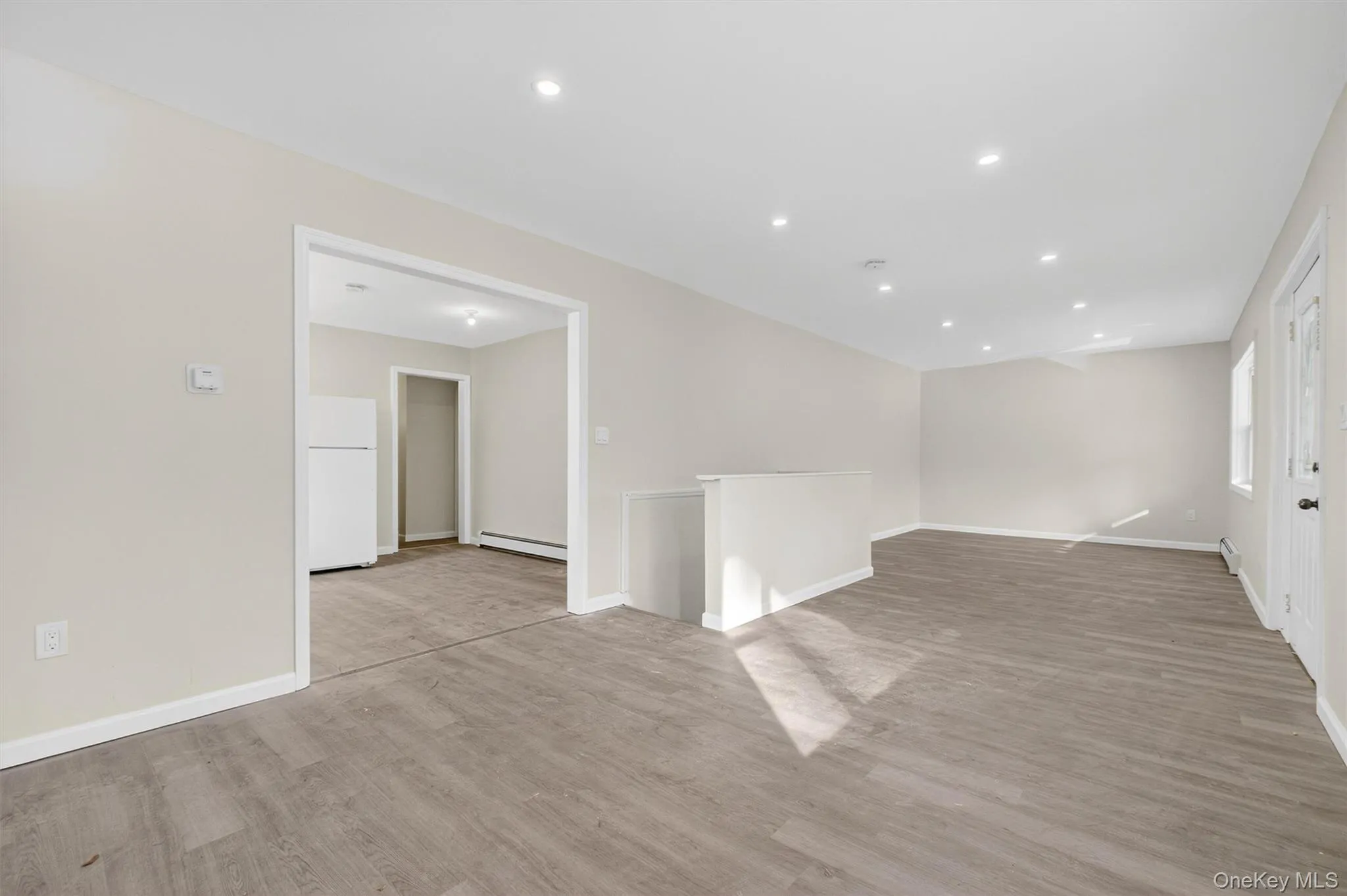 Unfurnished room with light wood-style floors, recessed lighting, and a baseboard heating unit Unfurnished room with light wood-style floors, recessed lighting, and a baseboard heating unit