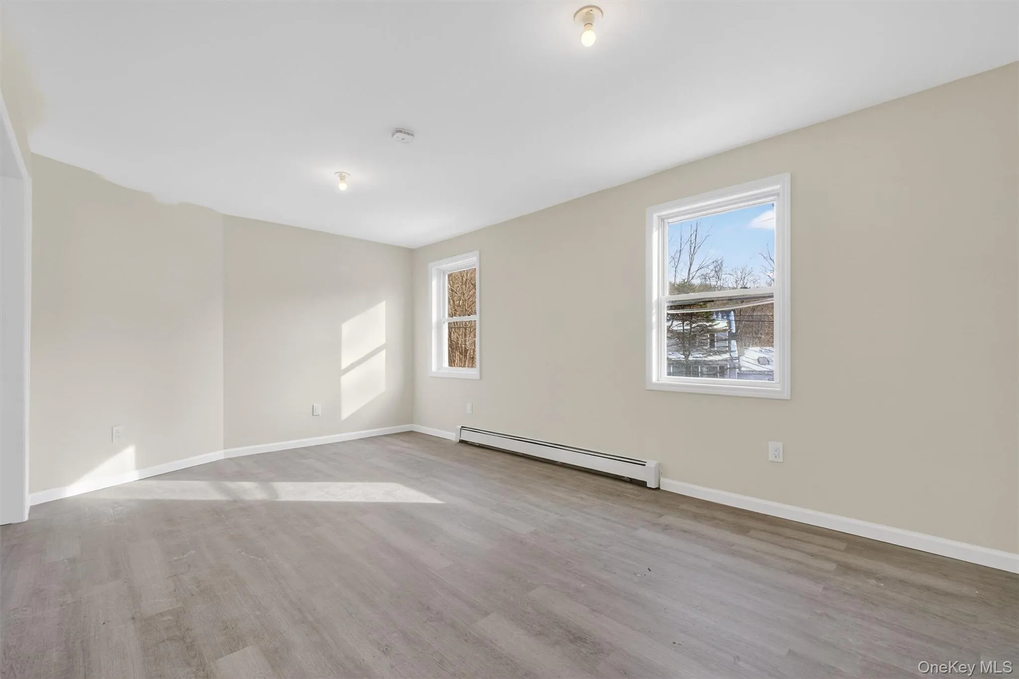 Spare room with baseboard heating and light wood-style flooring Spare room with baseboard heating and light wood-style flooring