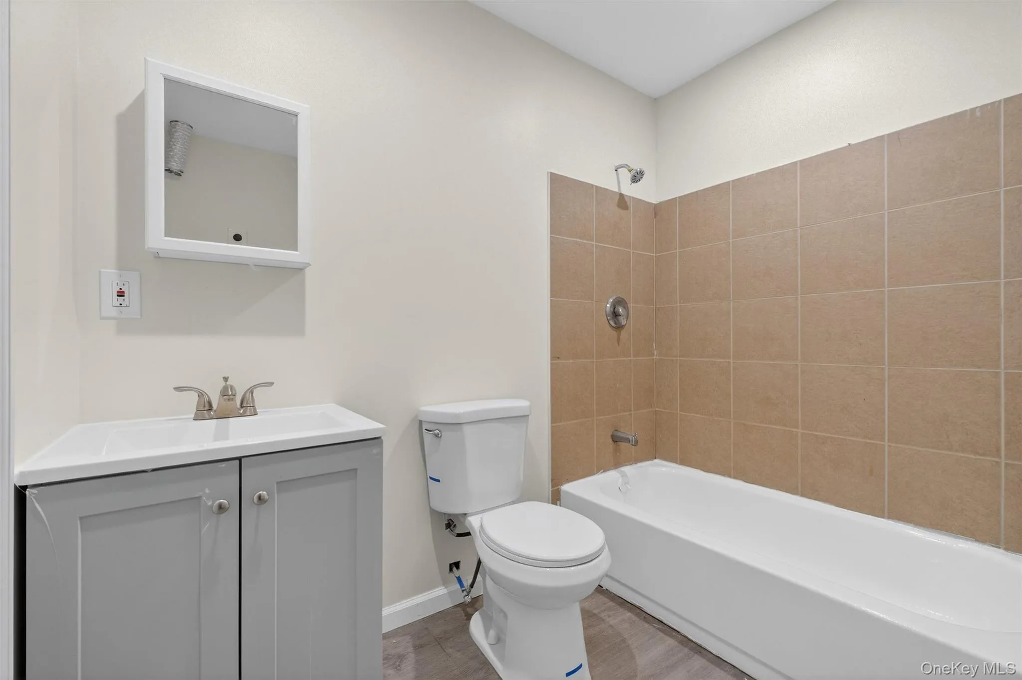 Full bathroom featuring shower / bath combination, vanity, and wood finished floors Full bathroom featuring shower / bath combination, vanity, and wood finished floors