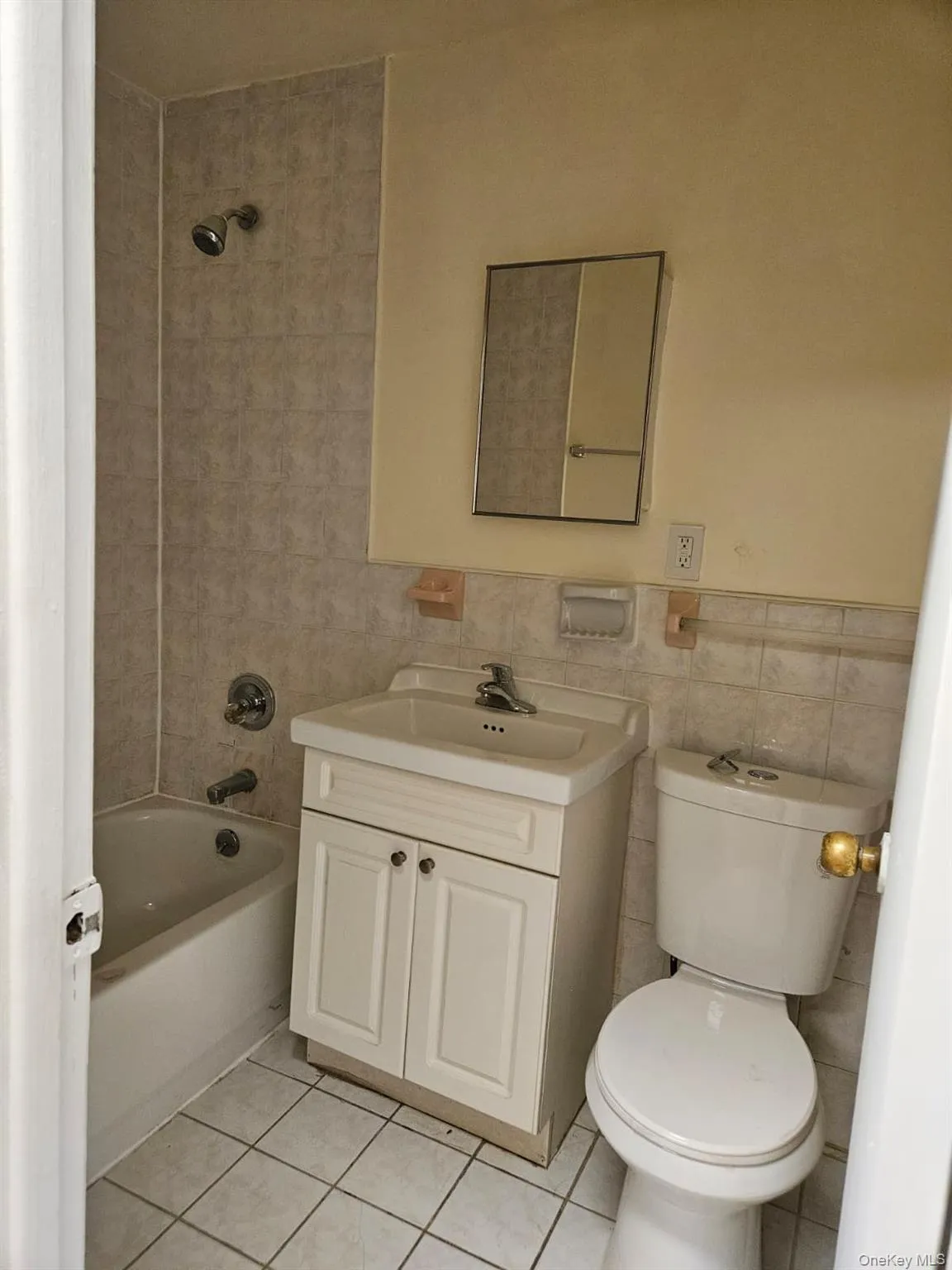 Bathroom with vanity, shower combination, tile walls, and light tile patterned floors Bathroom with vanity, shower combination, tile walls, and light tile patterned floors