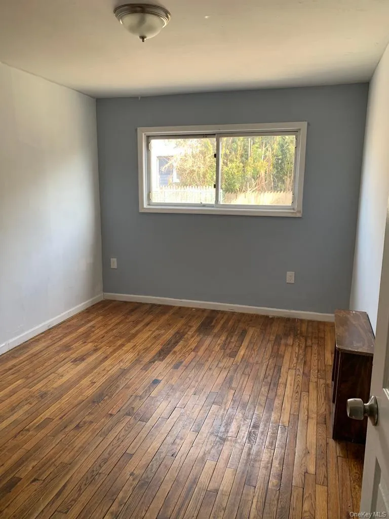 Unfurnished room with dark wood finished floors and baseboards Unfurnished room with dark wood finished floors and baseboards