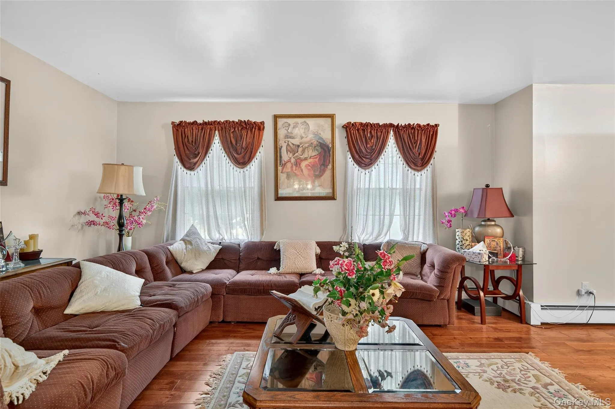 Living room with healthy amount of natural light, a baseboard radiator, and wood finished floors Living room with healthy amount of natural light, a baseboard radiator, and wood finished floors