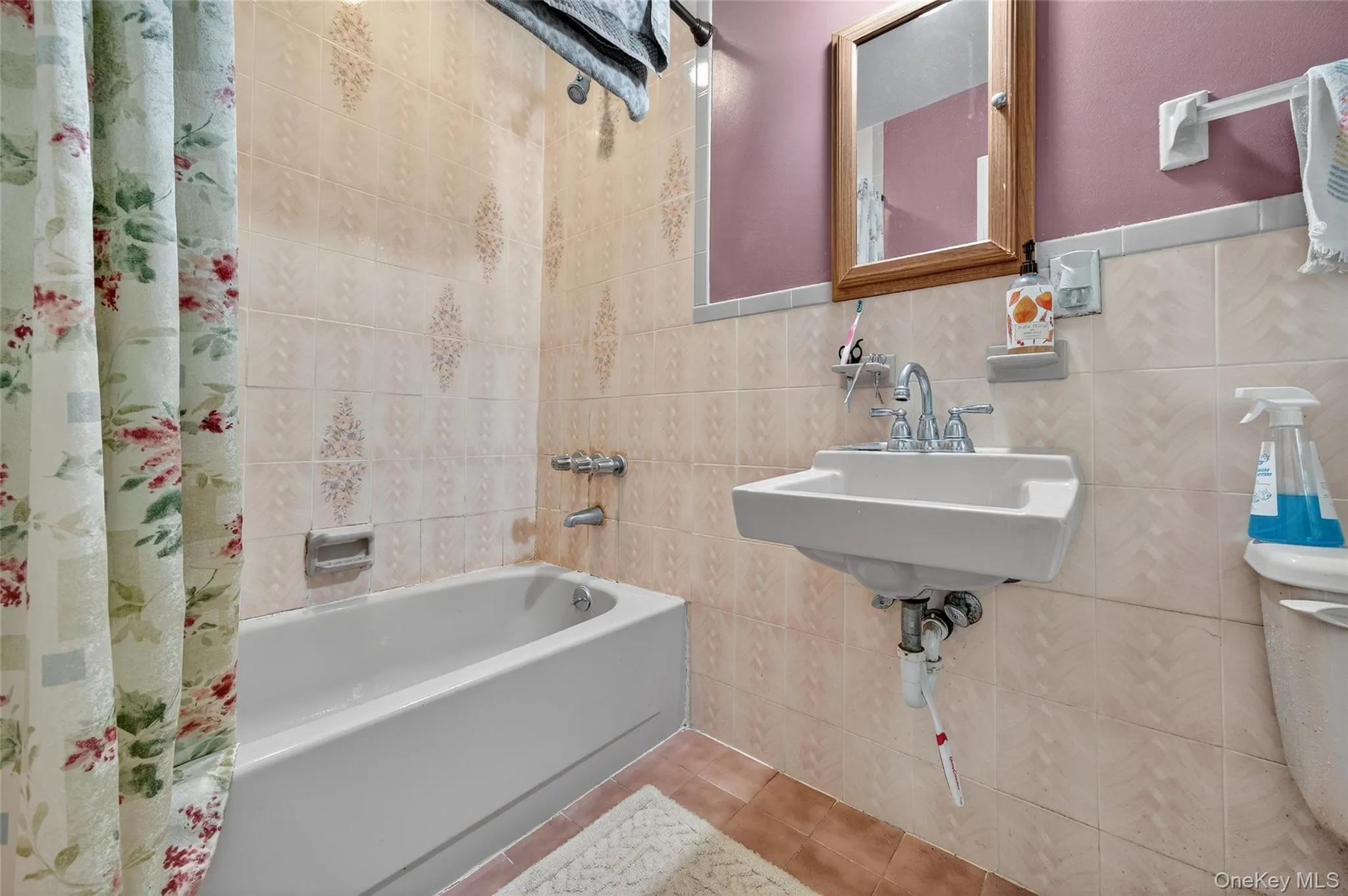 Bathroom with tile walls, shower / bath combo with shower curtain, and tile patterned floors Bathroom with tile walls, shower / bath combo with shower curtain, and tile patterned floors