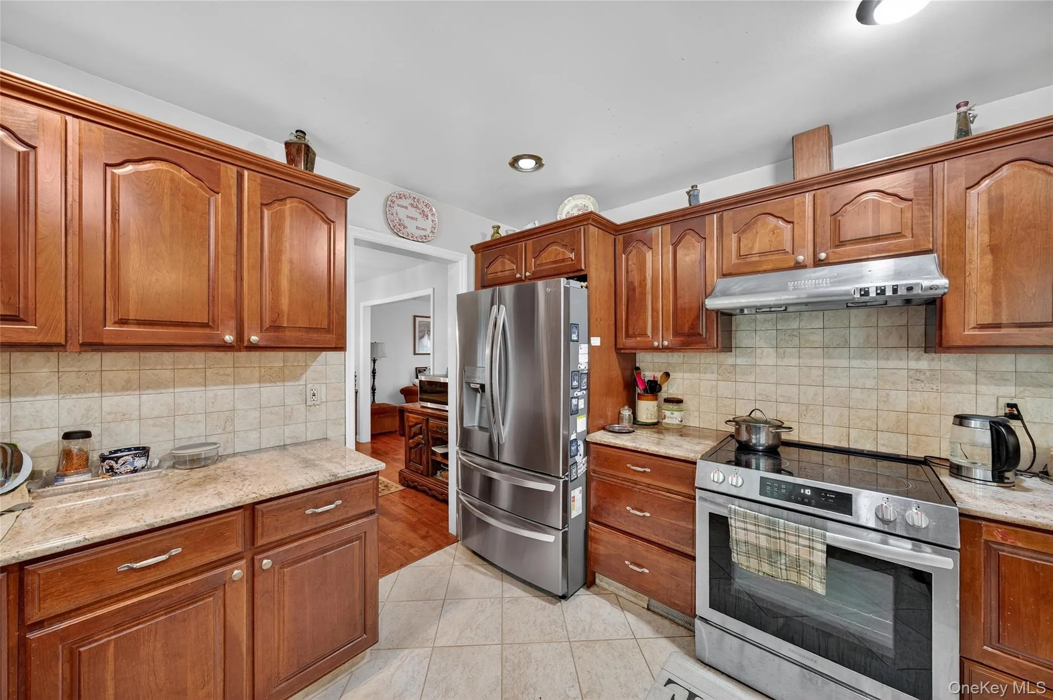 Kitchen featuring appliances with stainless steel finishes, light stone counters, brown cabinets, and recessed lighting Kitchen featuring appliances with stainless steel finishes, light stone counters, brown cabinets, and recessed lighting