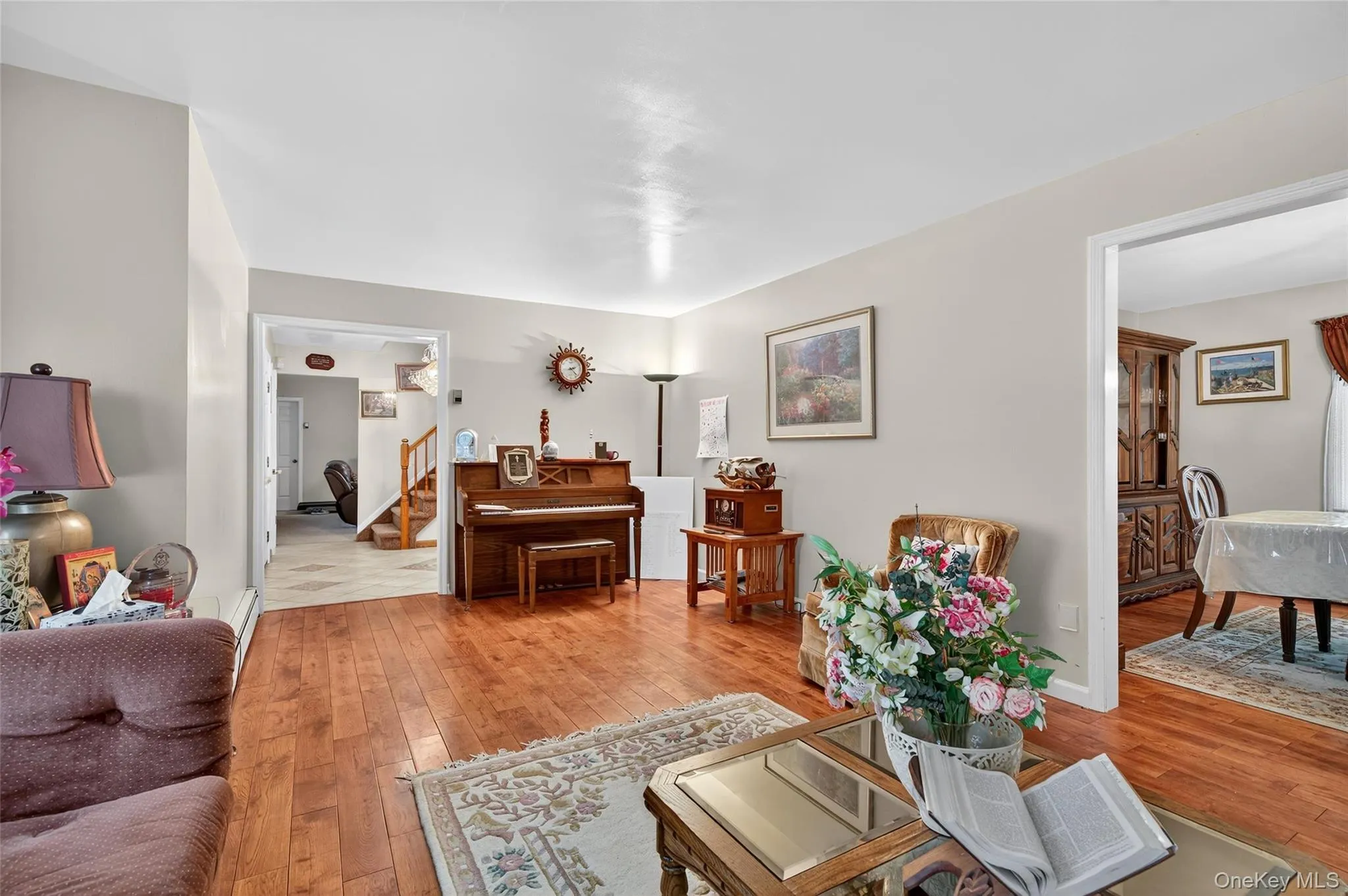 Living area with light wood-style flooring, stairway, and a baseboard radiator Living area with light wood-style flooring, stairway, and a baseboard radiator