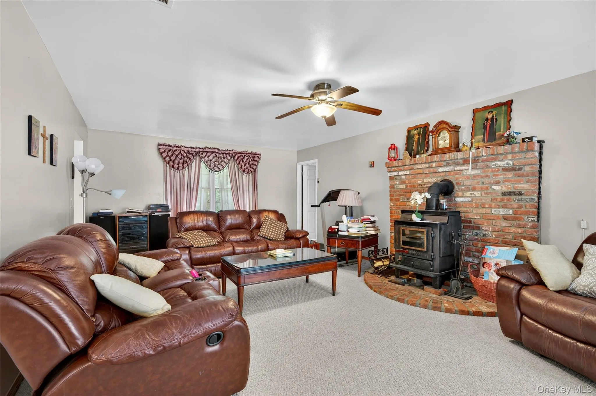 Carpeted living area with a wood stove, ceiling fan, and wine cooler Carpeted living area with a wood stove, ceiling fan, and wine cooler