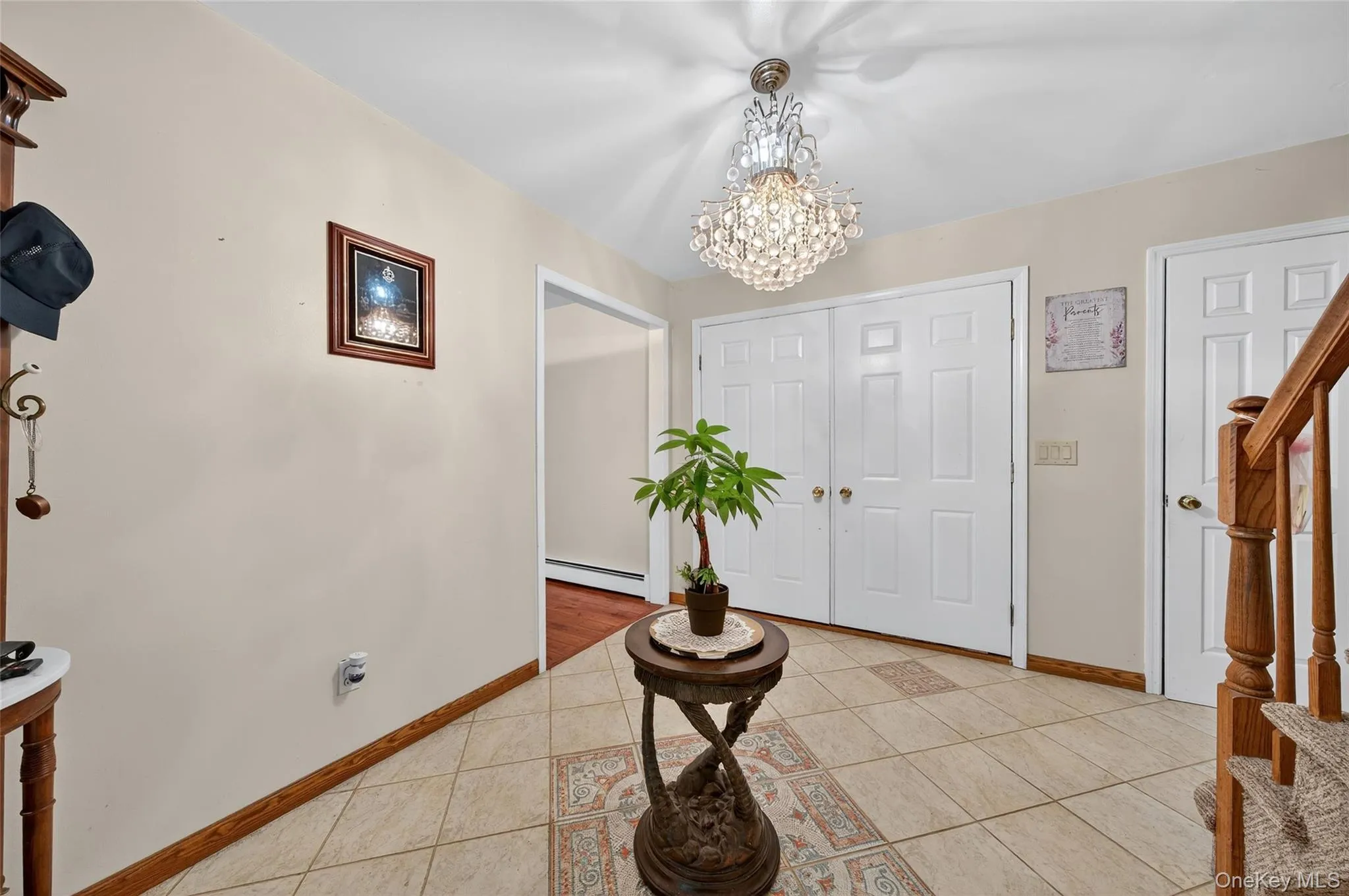 Entryway featuring light tile patterned floors, a chandelier, stairway, and a baseboard heating unit Entryway featuring light tile patterned floors, a chandelier, stairway, and a baseboard heating unit