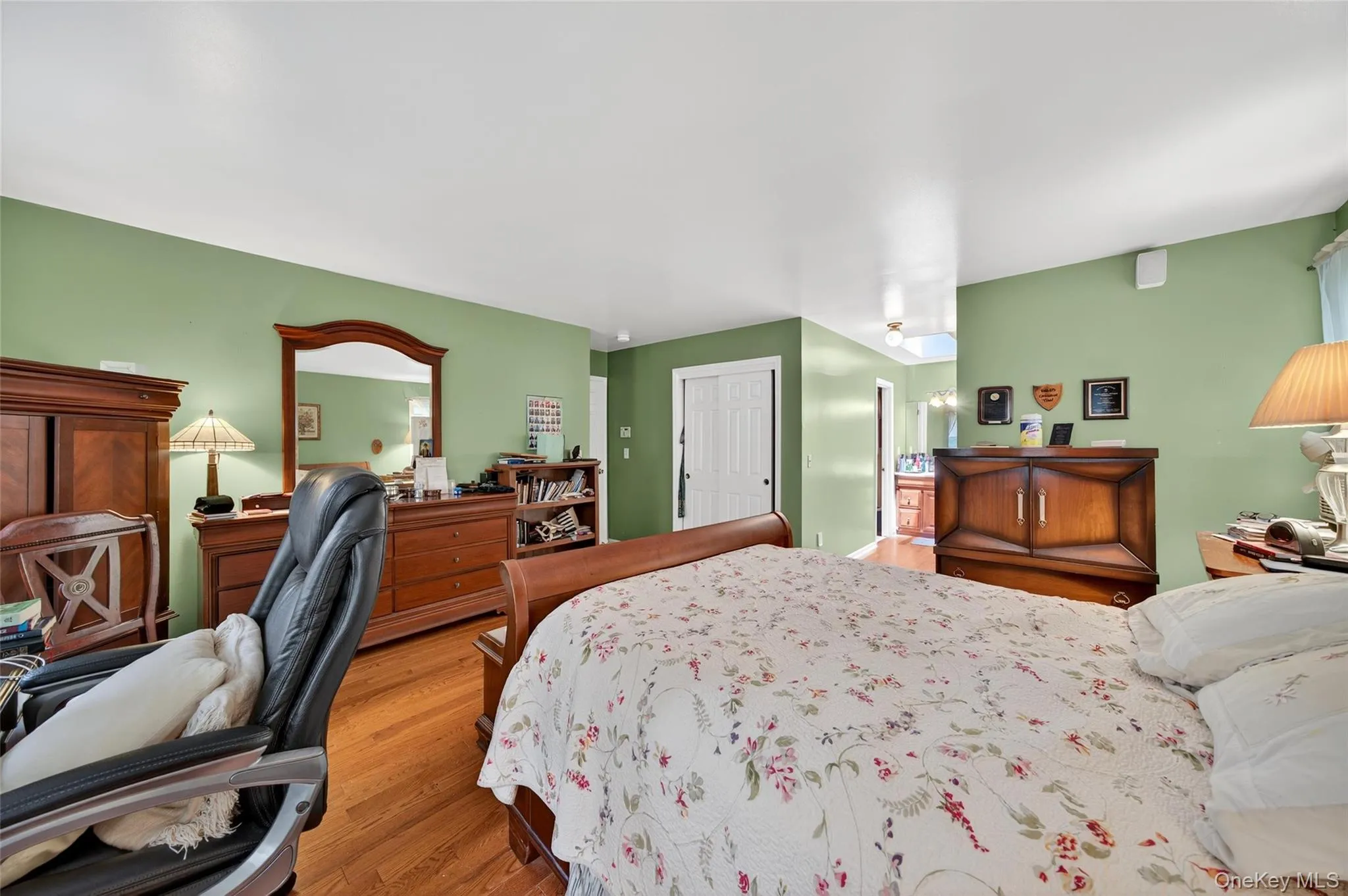 Bedroom featuring light wood finished floors and ensuite bath Bedroom featuring light wood finished floors and ensuite bath