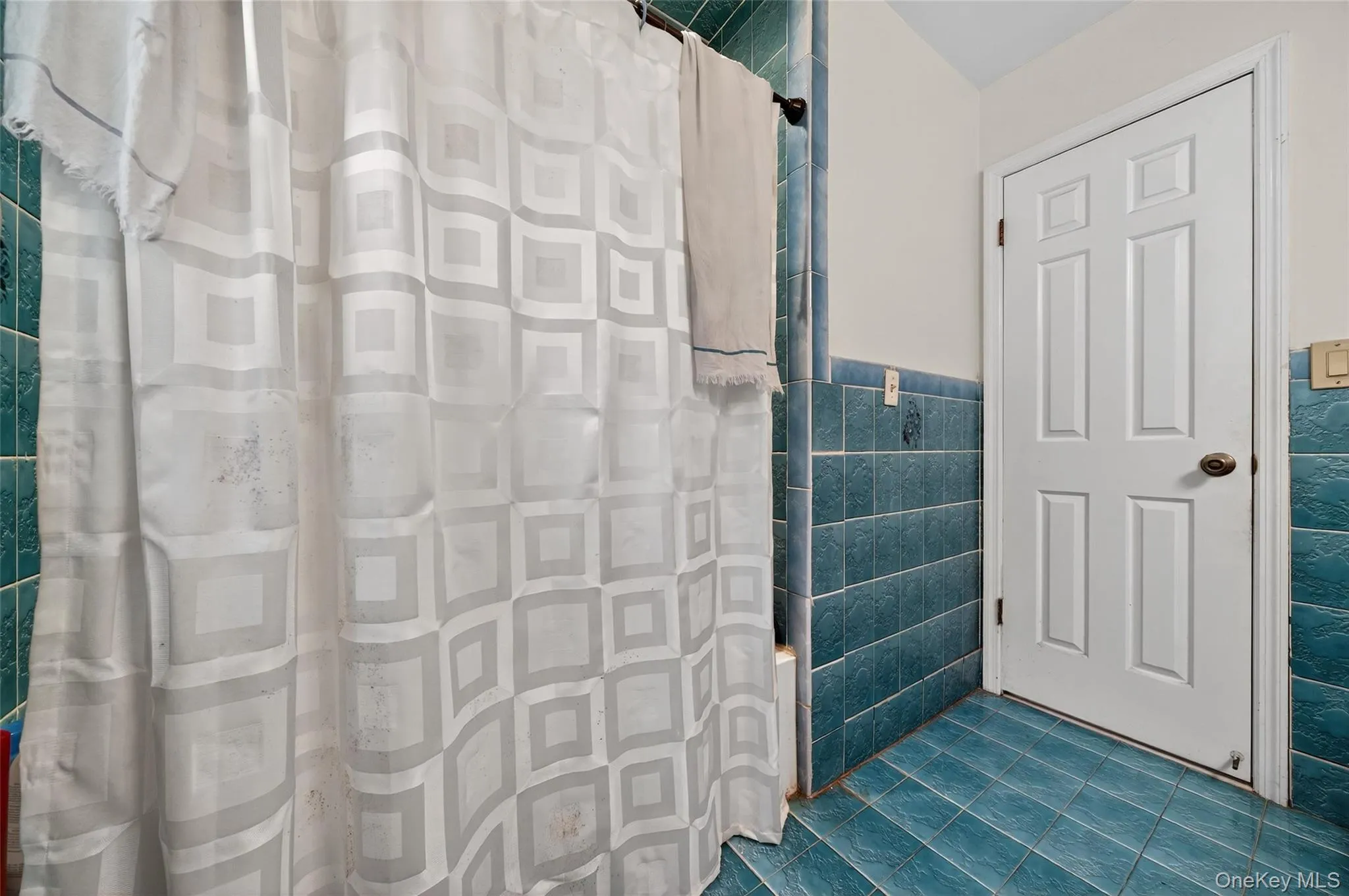 Bathroom featuring tile walls, dark tile patterned floors, and a wainscoted wall Bathroom featuring tile walls, dark tile patterned floors, and a wainscoted wall