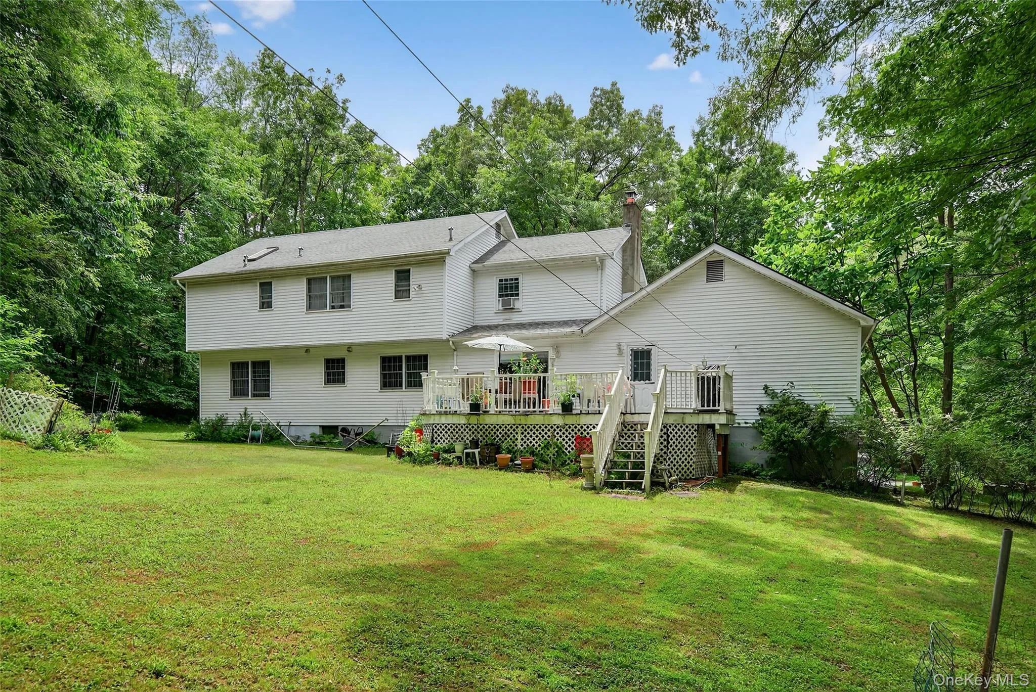 Rear view of house with a chimney, a lawn, stairway, and a wooden deck Rear view of house with a chimney, a lawn, stairway, and a wooden deck