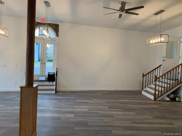 Foyer featuring dark wood finished floors, french doors, a ceiling fan, stairway, and a chandelier Foyer featuring dark wood finished floors, french doors, a ceiling fan, stairway, and a chandelier