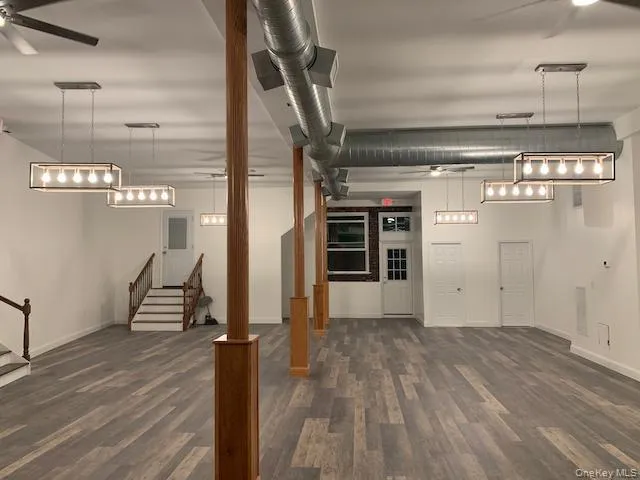 Below grade area featuring ceiling fan, dark wood-style flooring, and stairway Below grade area featuring ceiling fan, dark wood-style flooring, and stairway