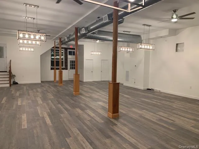 Below grade area with ceiling fan, dark wood finished floors, and stairs Below grade area with ceiling fan, dark wood finished floors, and stairs