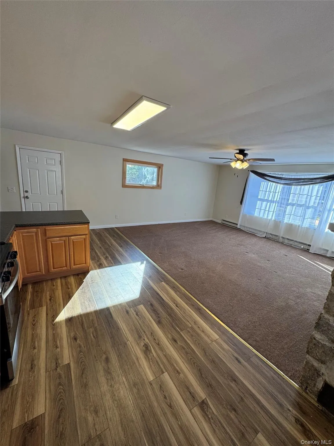 Unfurnished living room with dark colored carpet, a ceiling fan, and dark wood-style floors Unfurnished living room with dark colored carpet, a ceiling fan, and dark wood-style floors