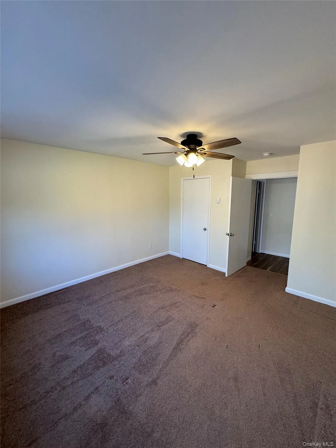 Empty room featuring dark colored carpet and ceiling fan Empty room featuring dark colored carpet and ceiling fan