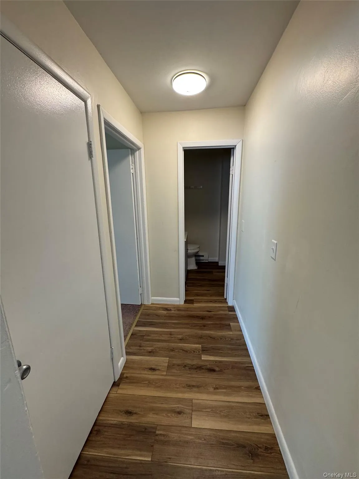 Hallway featuring dark wood-style floors and baseboards Hallway featuring dark wood-style floors and baseboards
