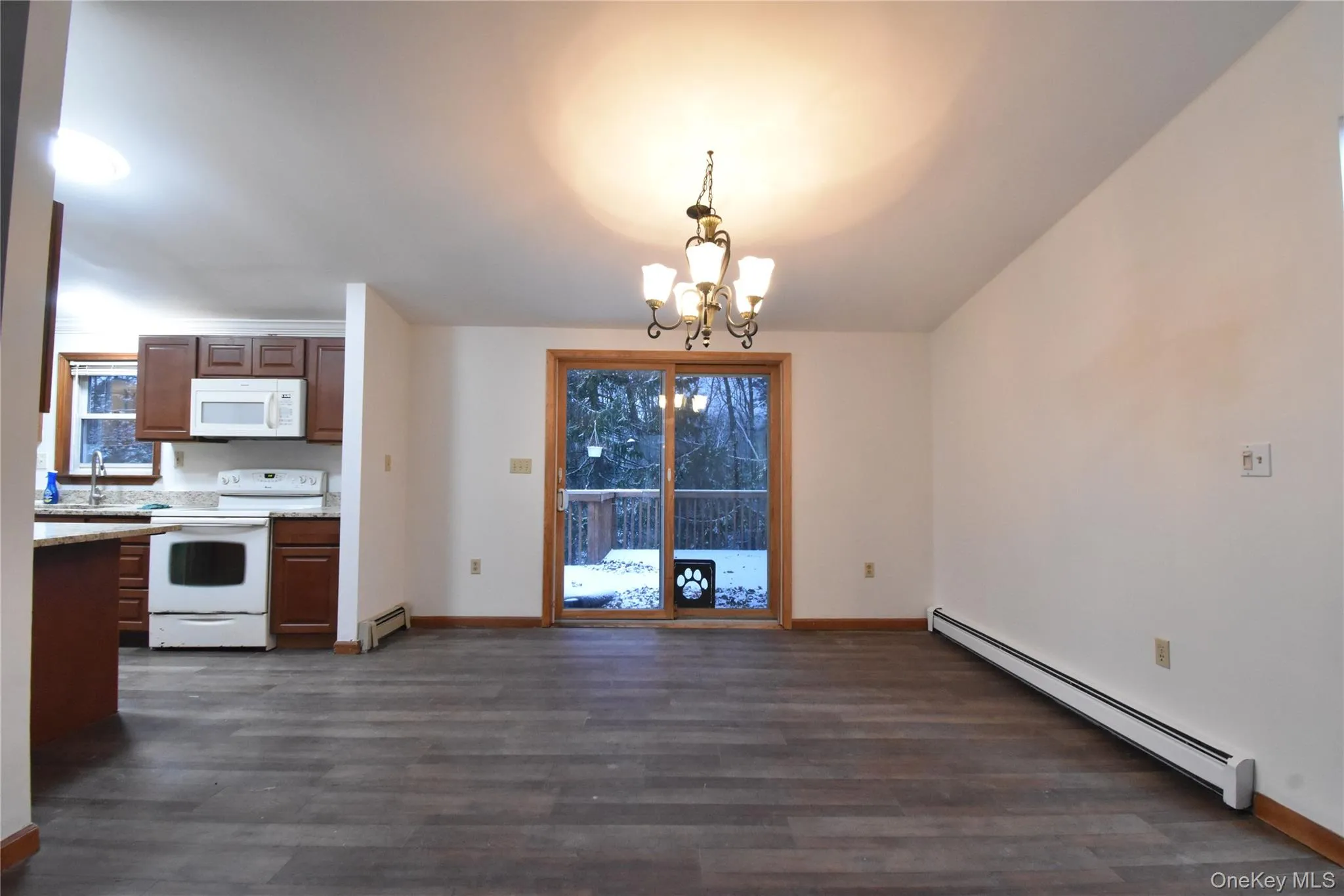 Kitchen featuring a baseboard radiator, white appliances, dark wood finished floors, and a chandelier Kitchen featuring a baseboard radiator, white appliances, dark wood finished floors, and a chandelier